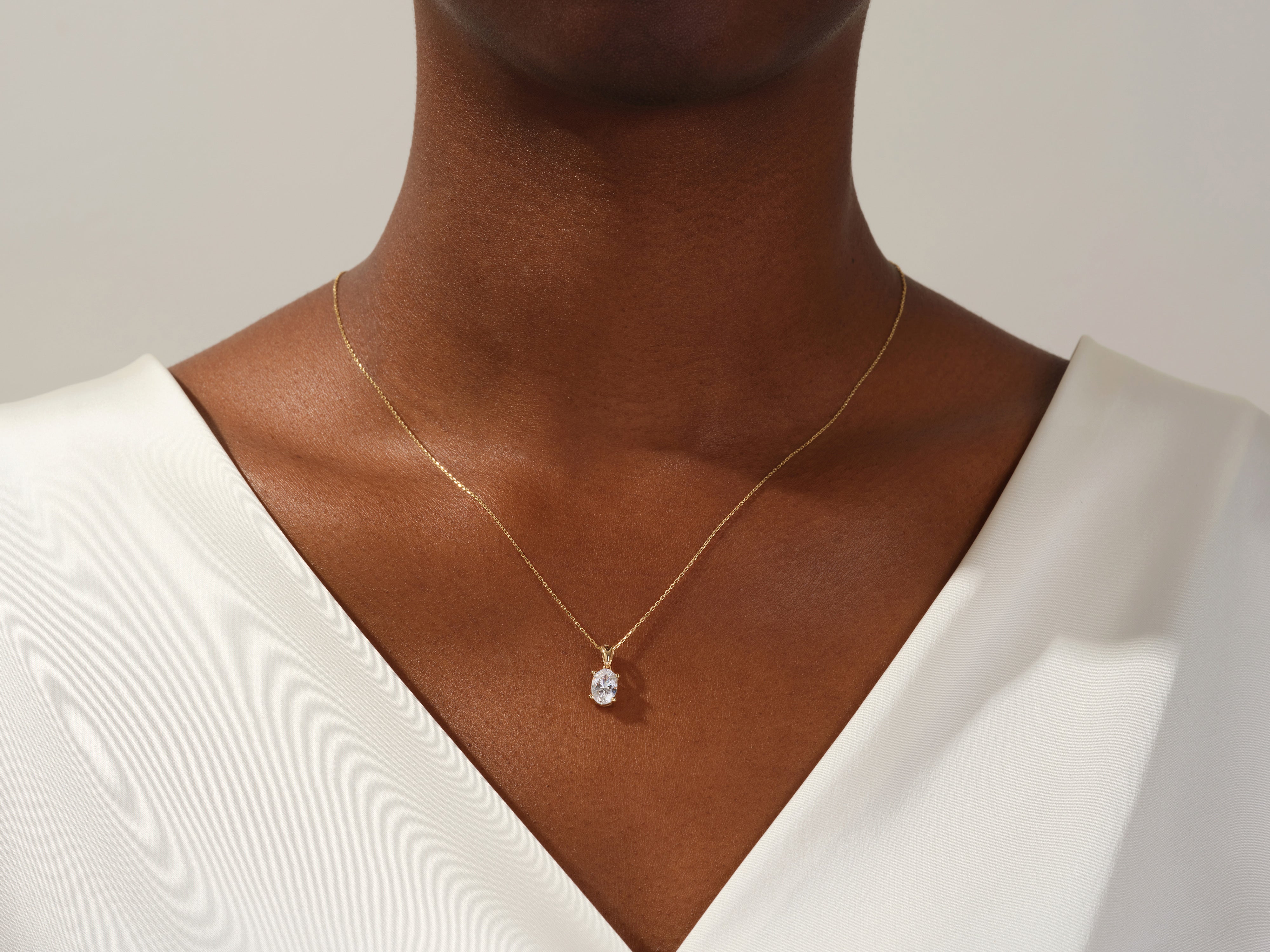 Gold necklace with oval diamond pendant on model