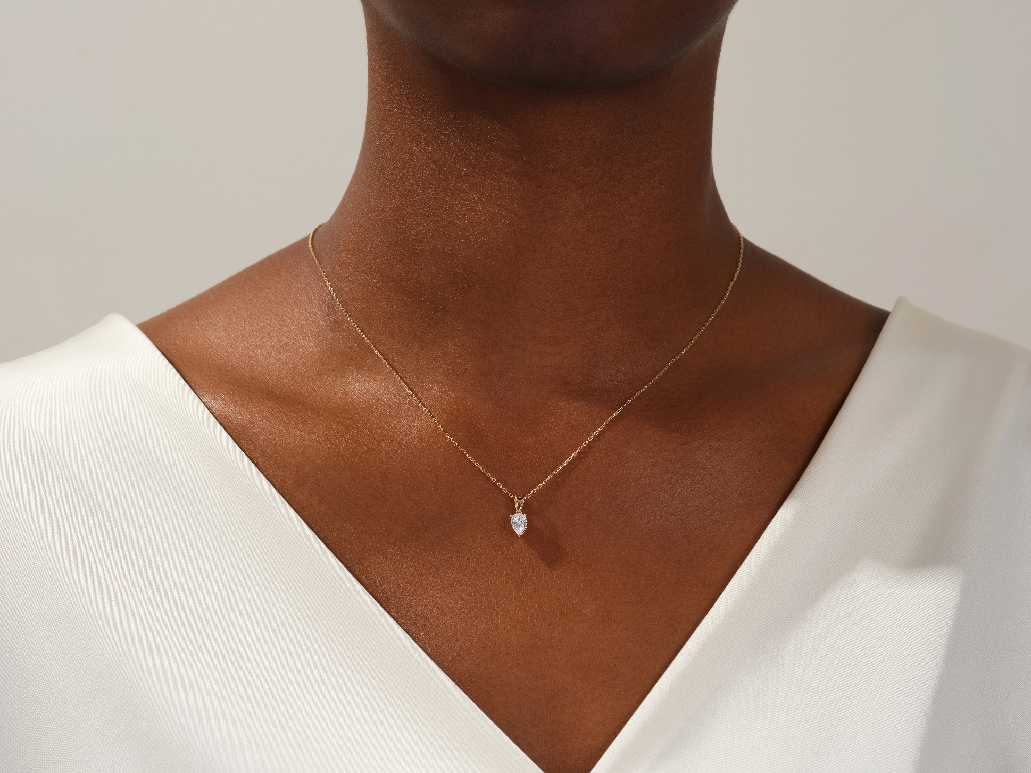 Gold necklace with pear-shaped diamond pendant on a woman's neck