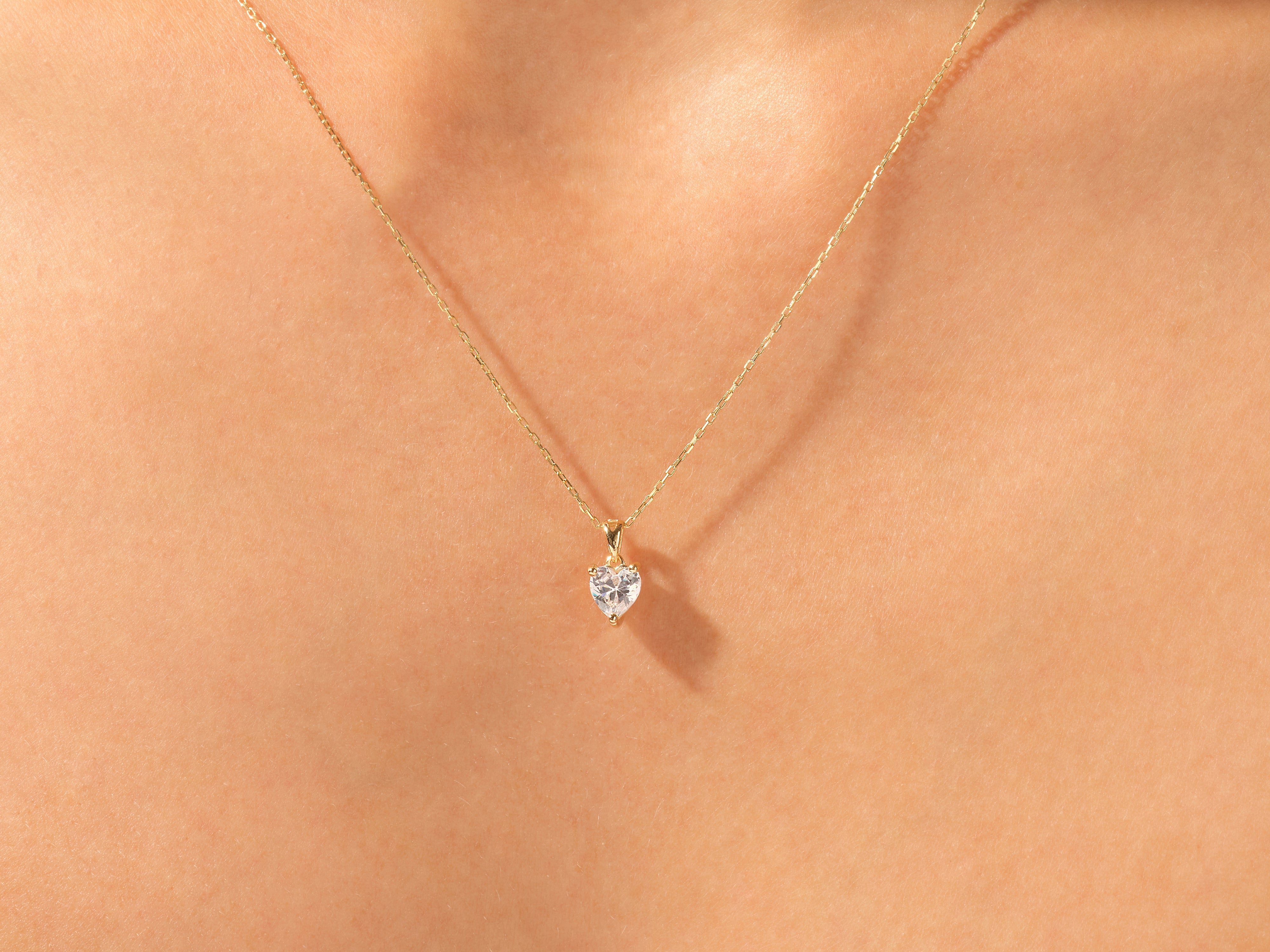 Gold heart necklace with diamond pendant on skin