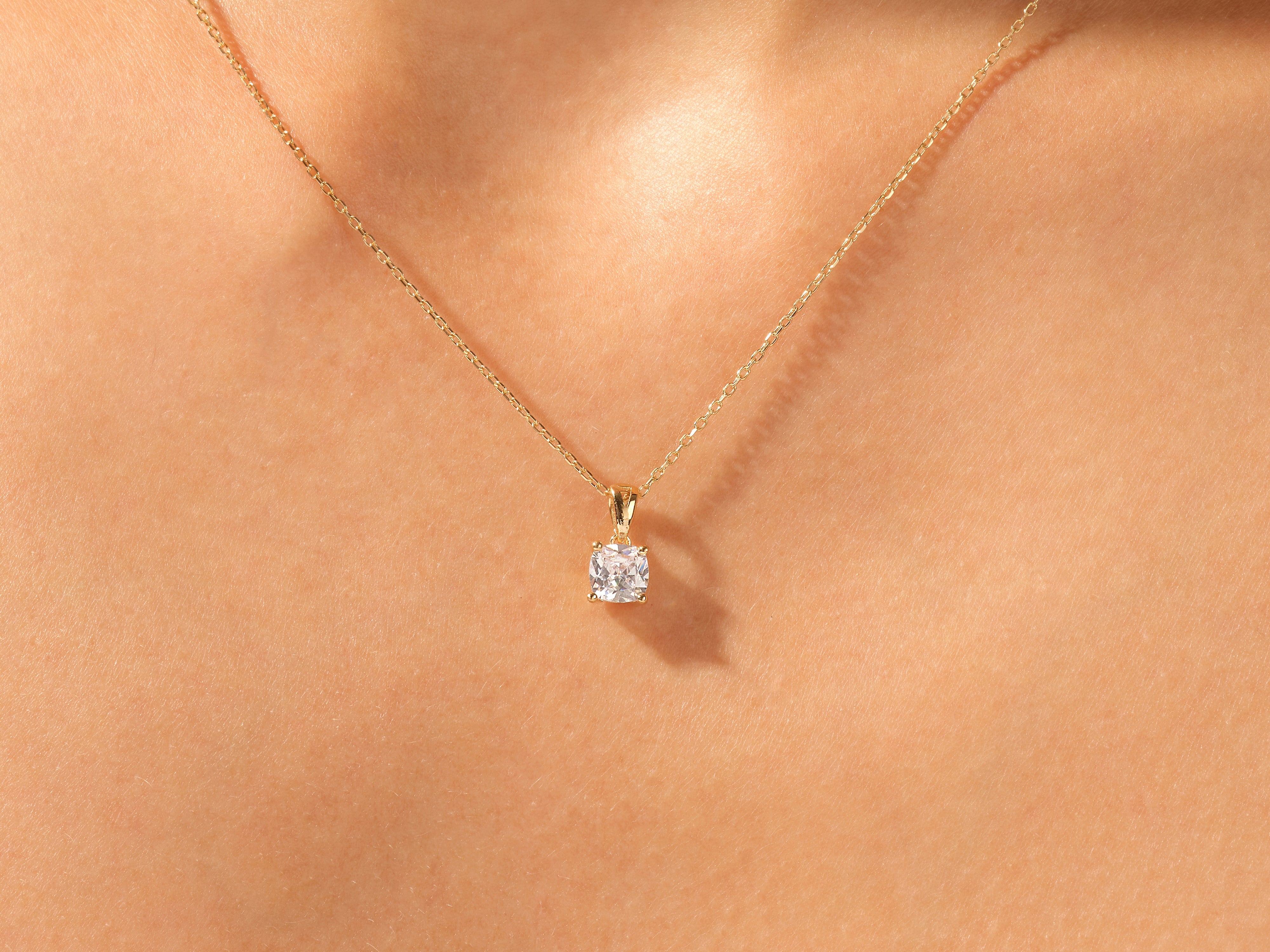 Gold necklace with a square diamond pendant on skin