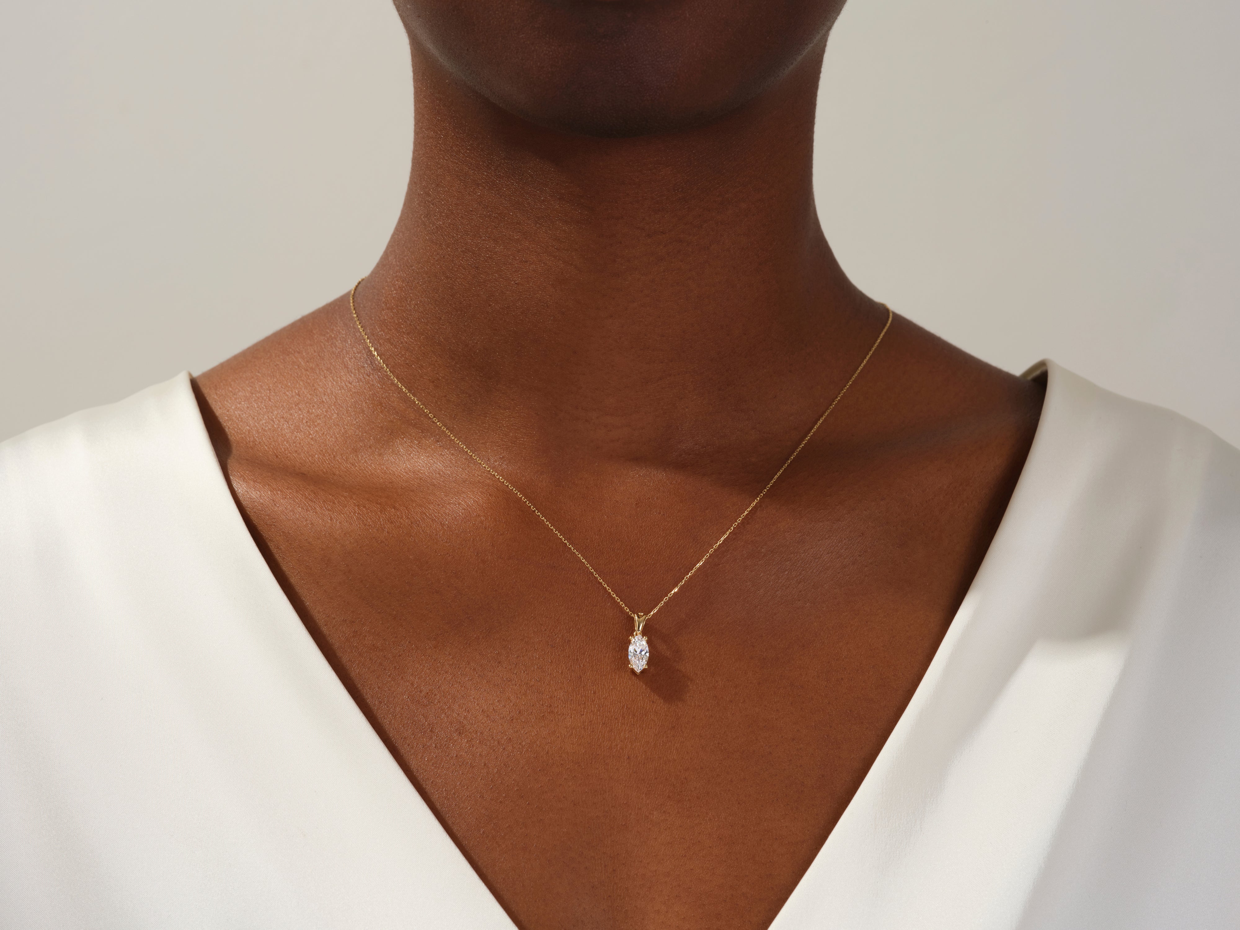 Gold necklace with marquise diamond pendant on woman's neck