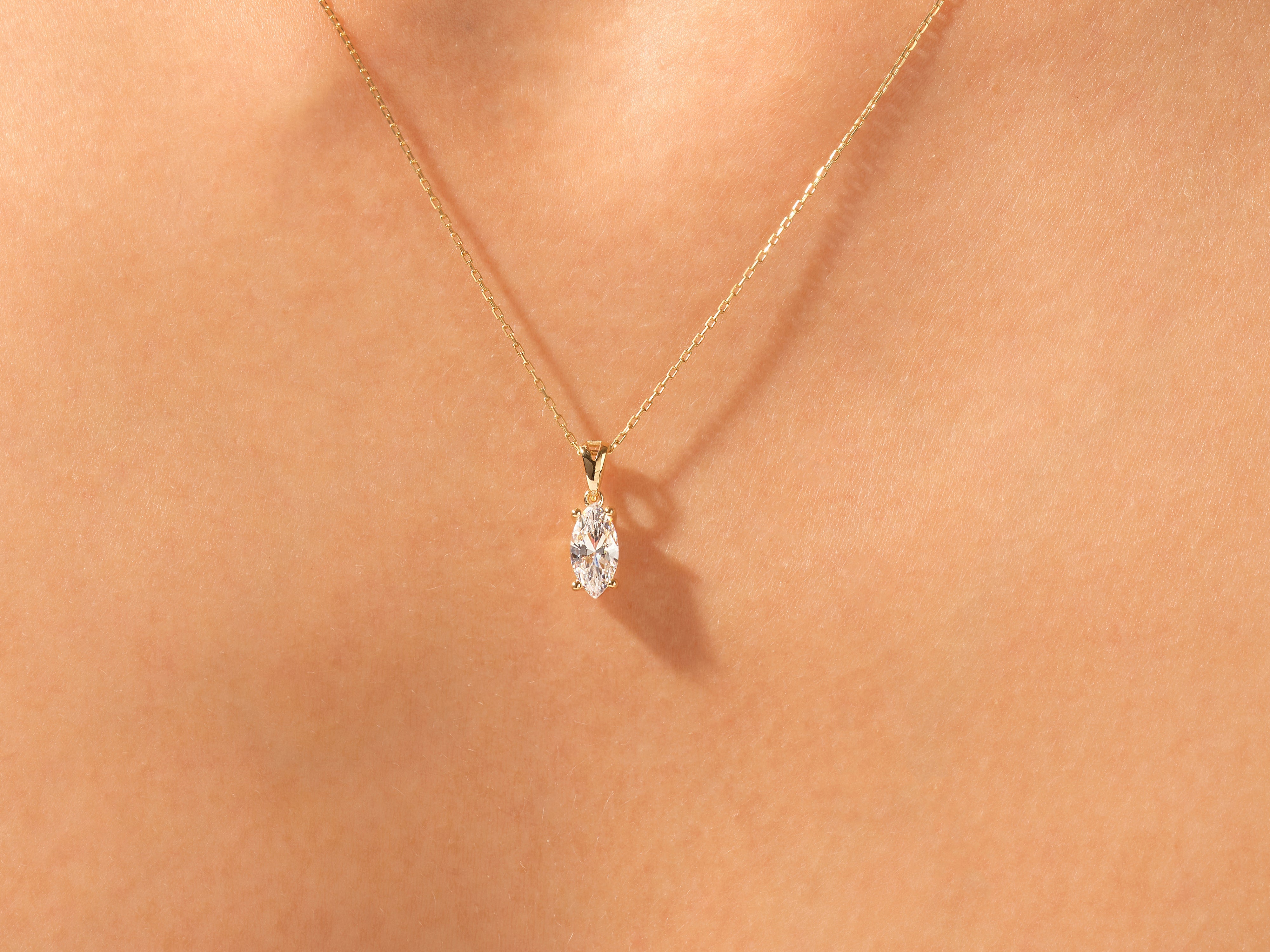 Gold necklace with marquise diamond pendant on skin
