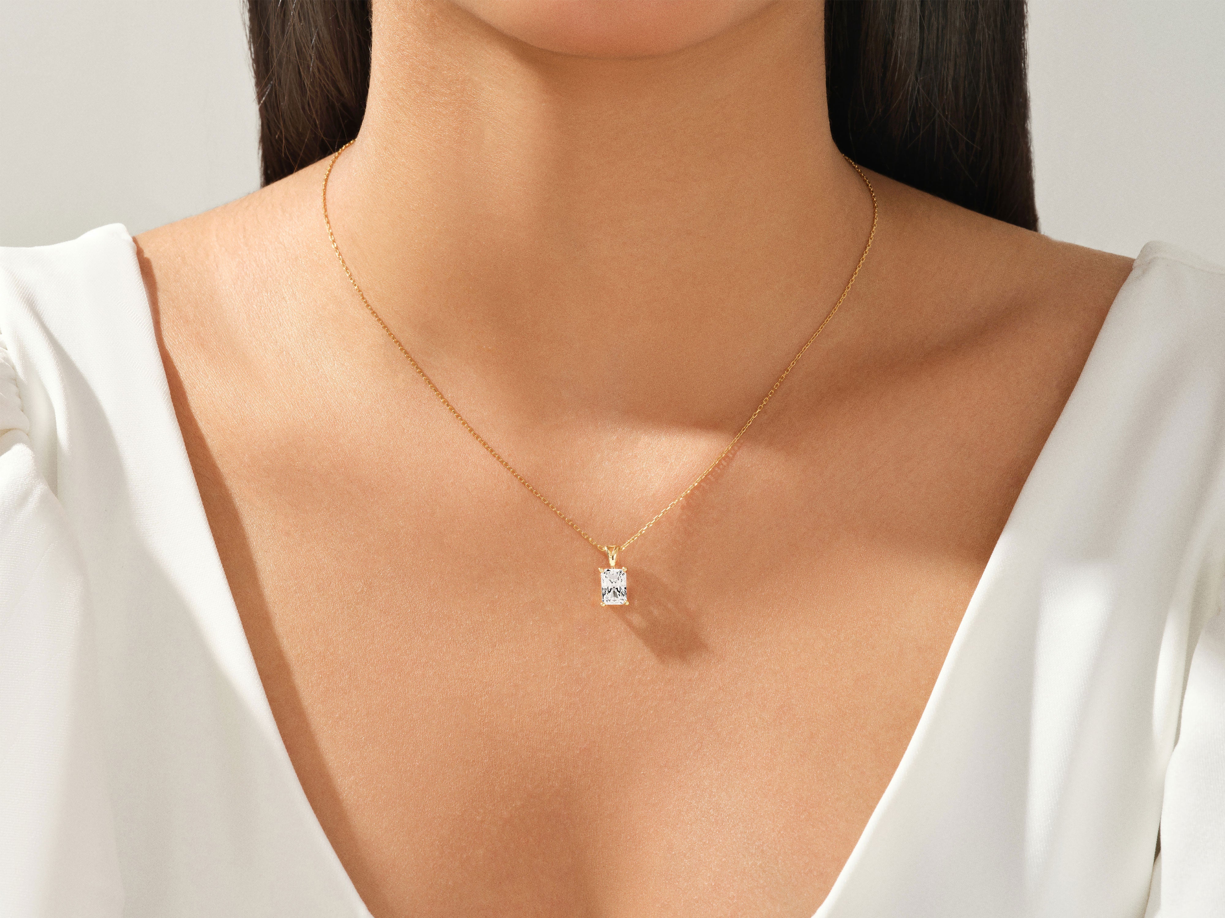 Gold necklace with a square-cut diamond pendant on a woman's neck