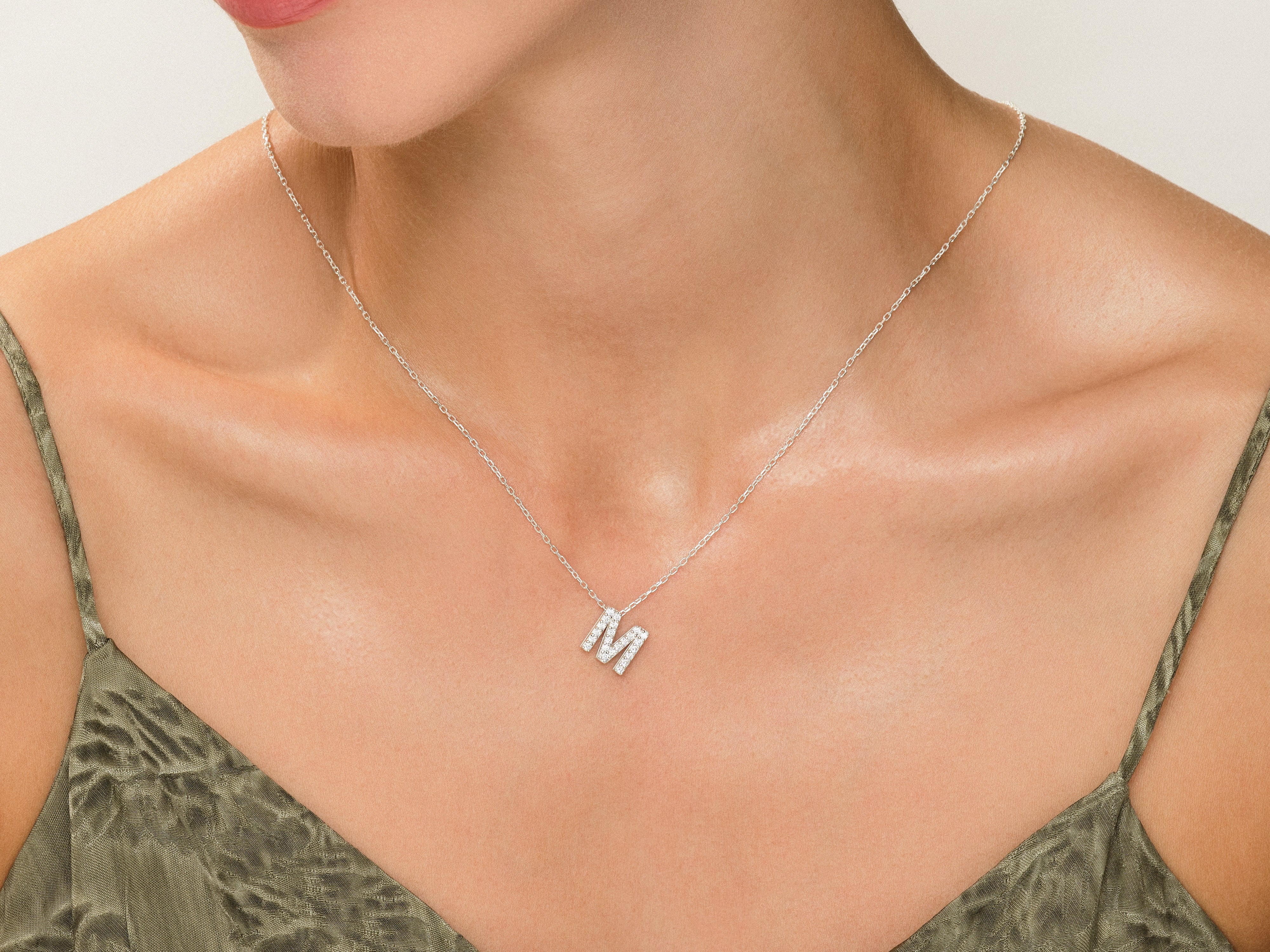Diamond initial 'M' necklace on a woman's neck