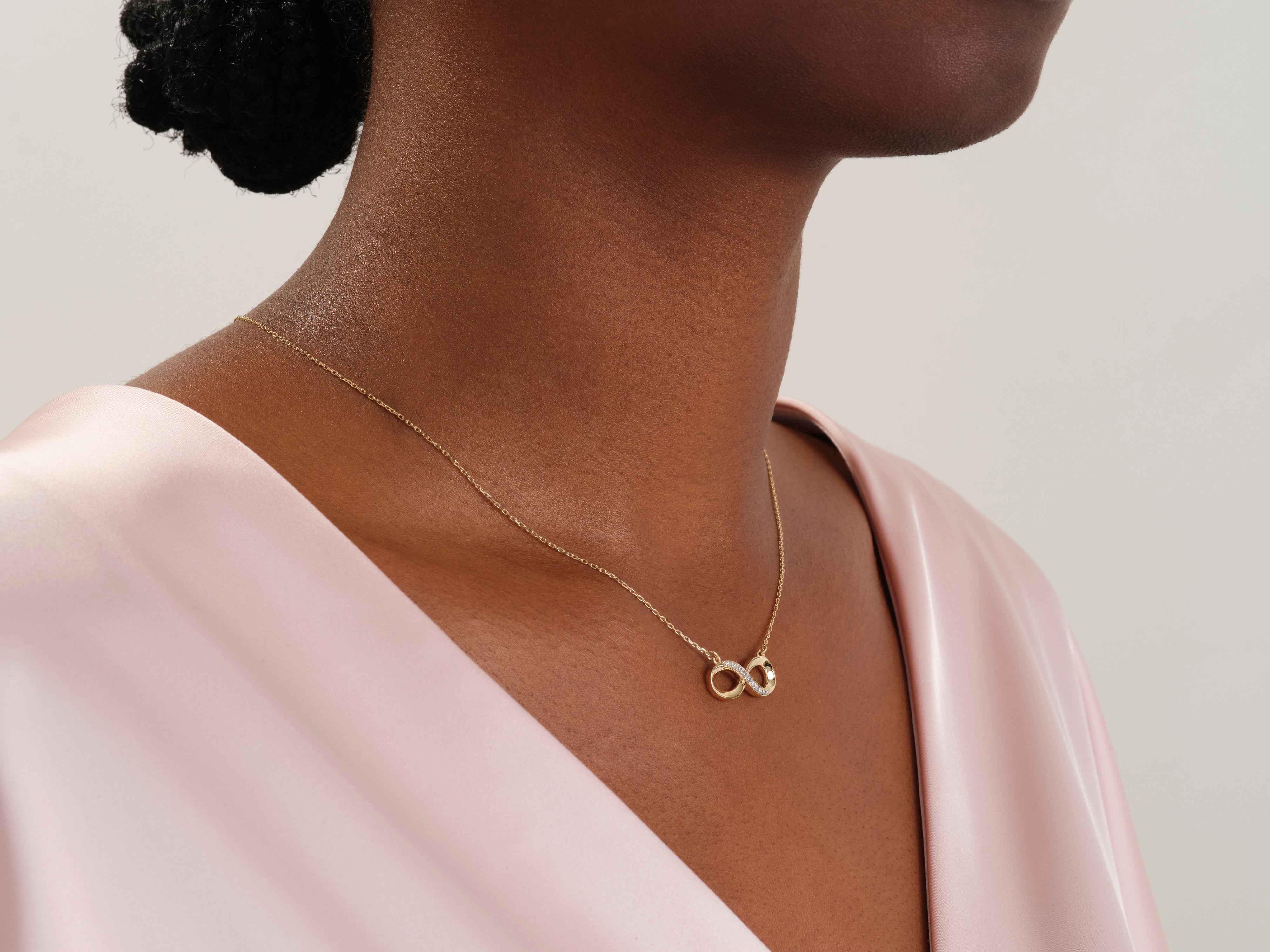 Gold infinity necklace with diamonds on a woman's neck