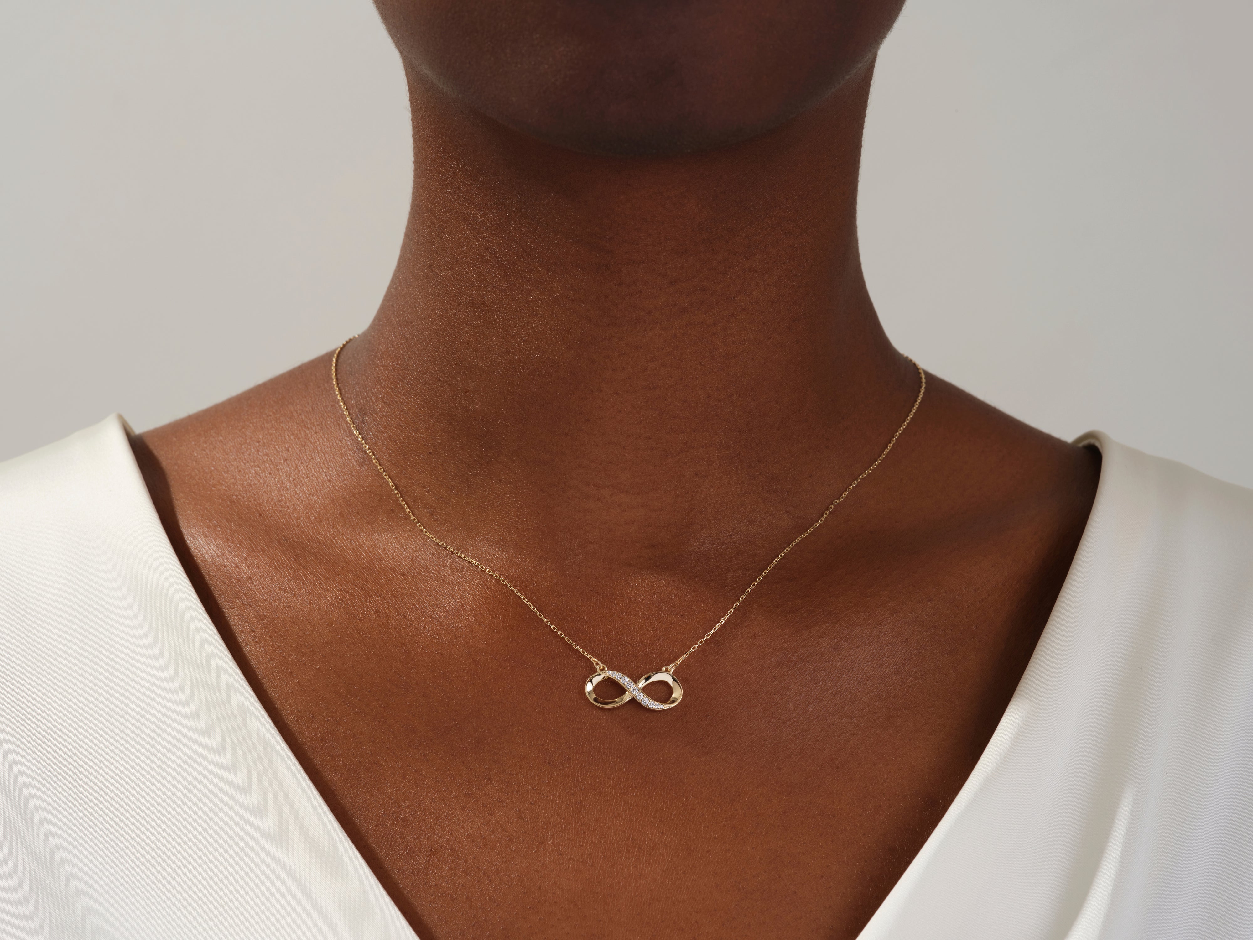 Gold infinity necklace with diamonds on a woman's neck