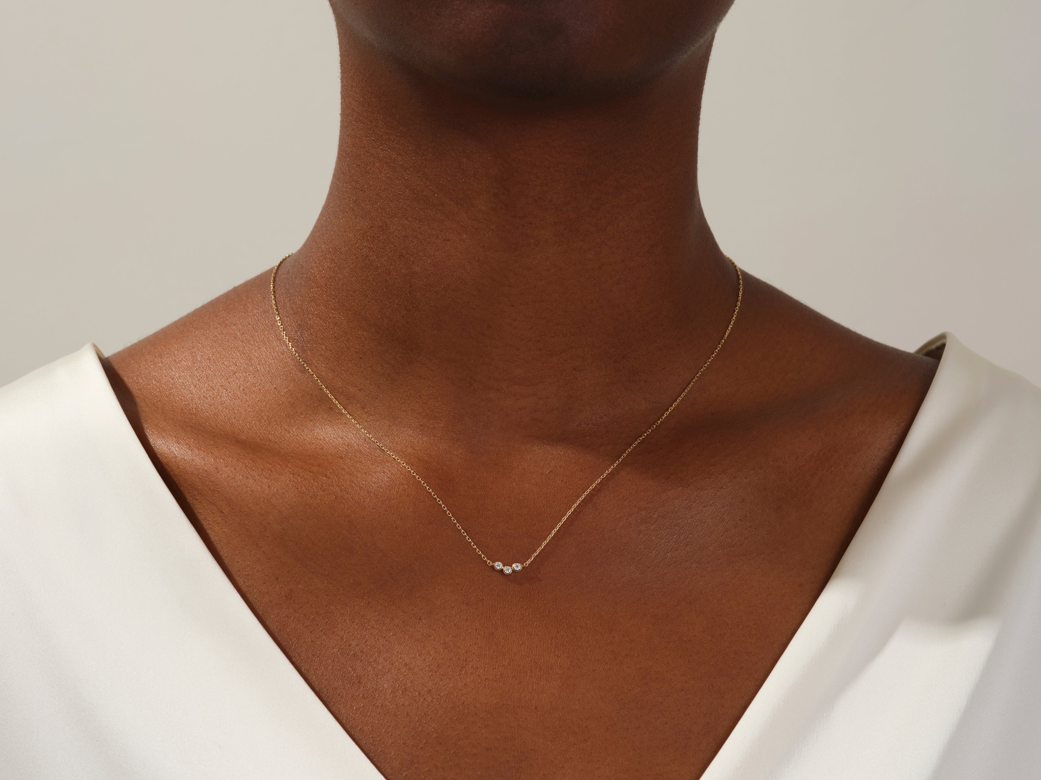 Gold necklace with three diamonds on a woman's neck
