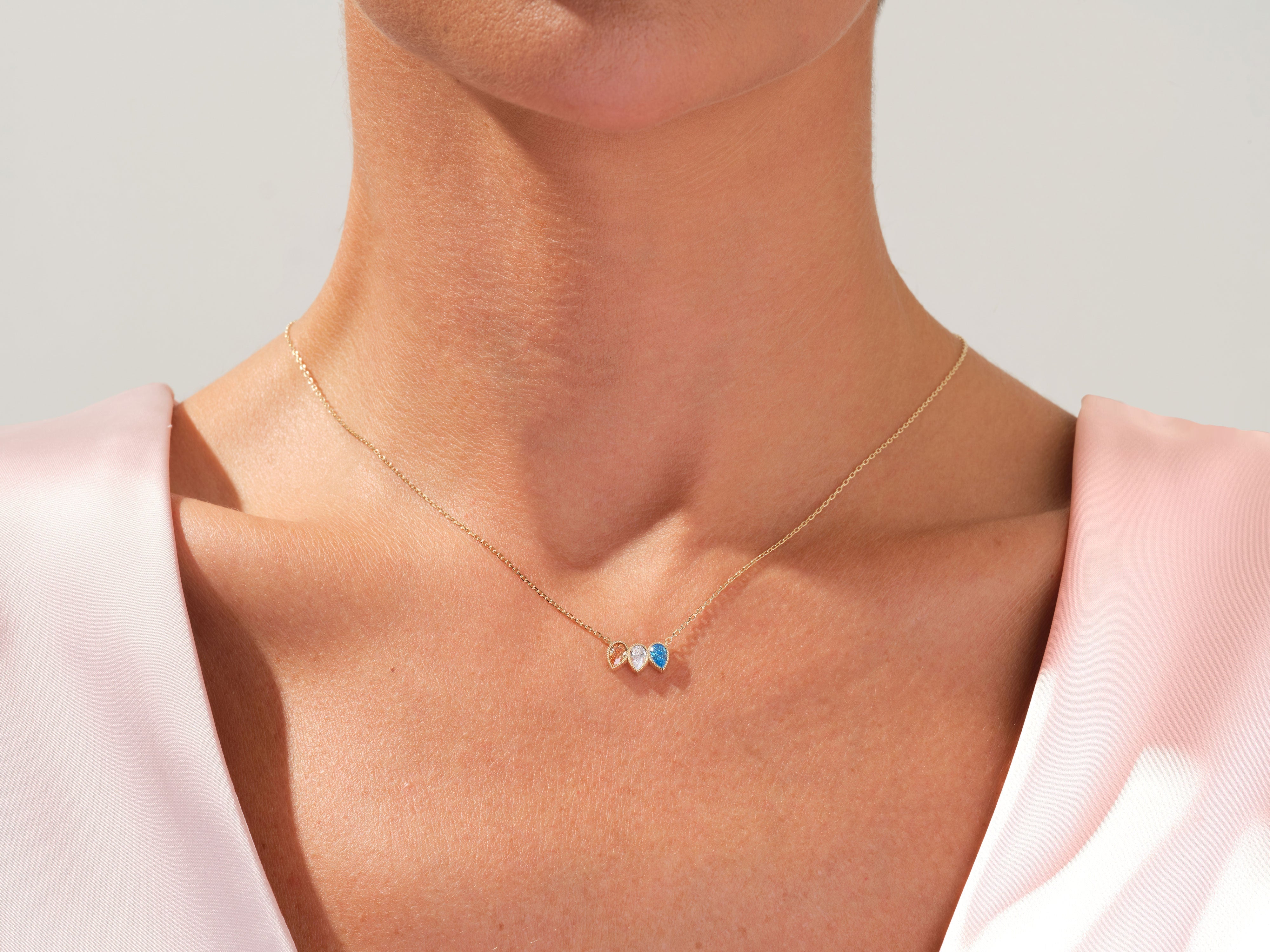 Gold necklace with two heart pendants, one blue, on a woman's neck