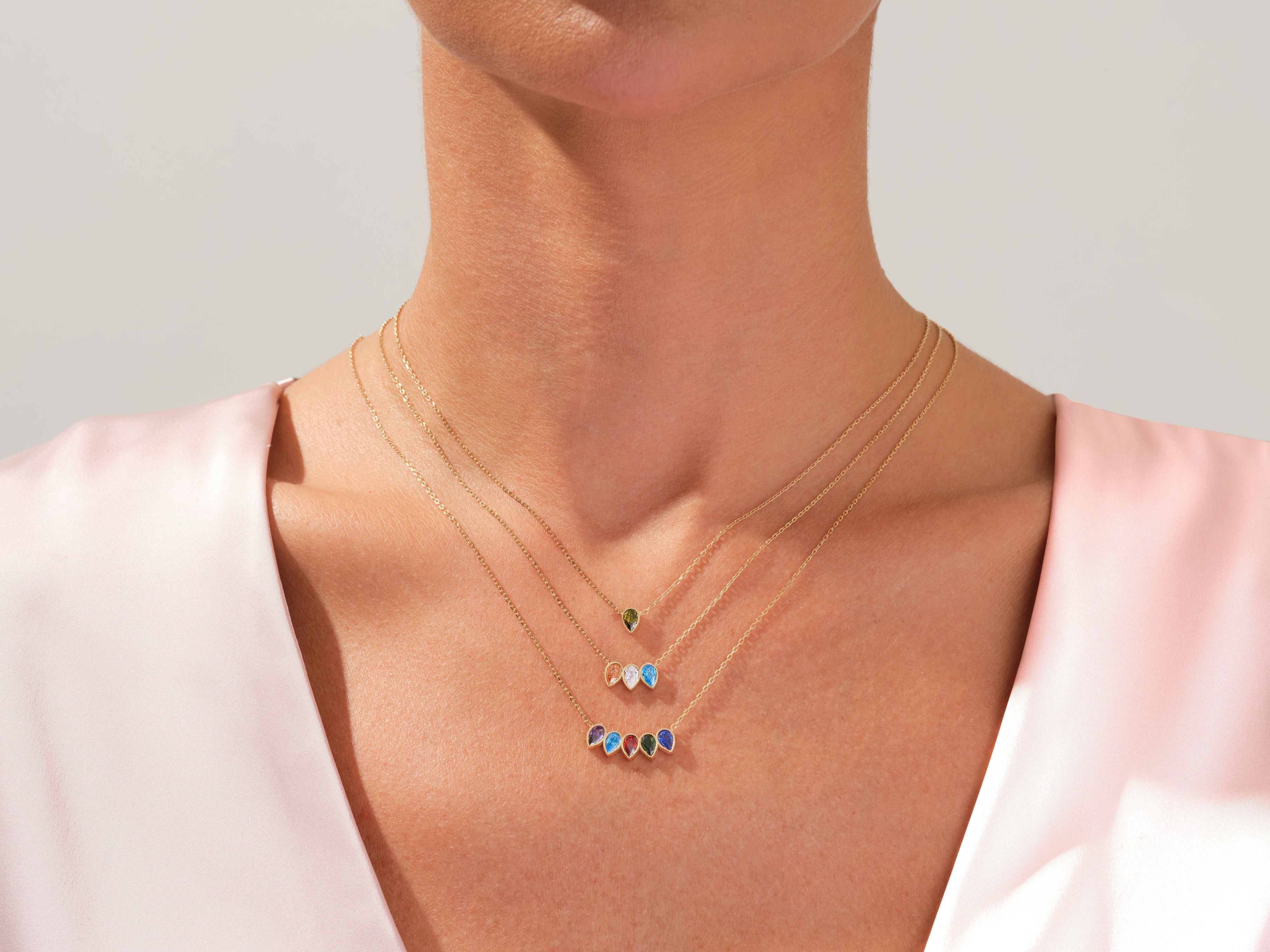 Gold necklaces with colorful gemstone pendants on a woman's neck