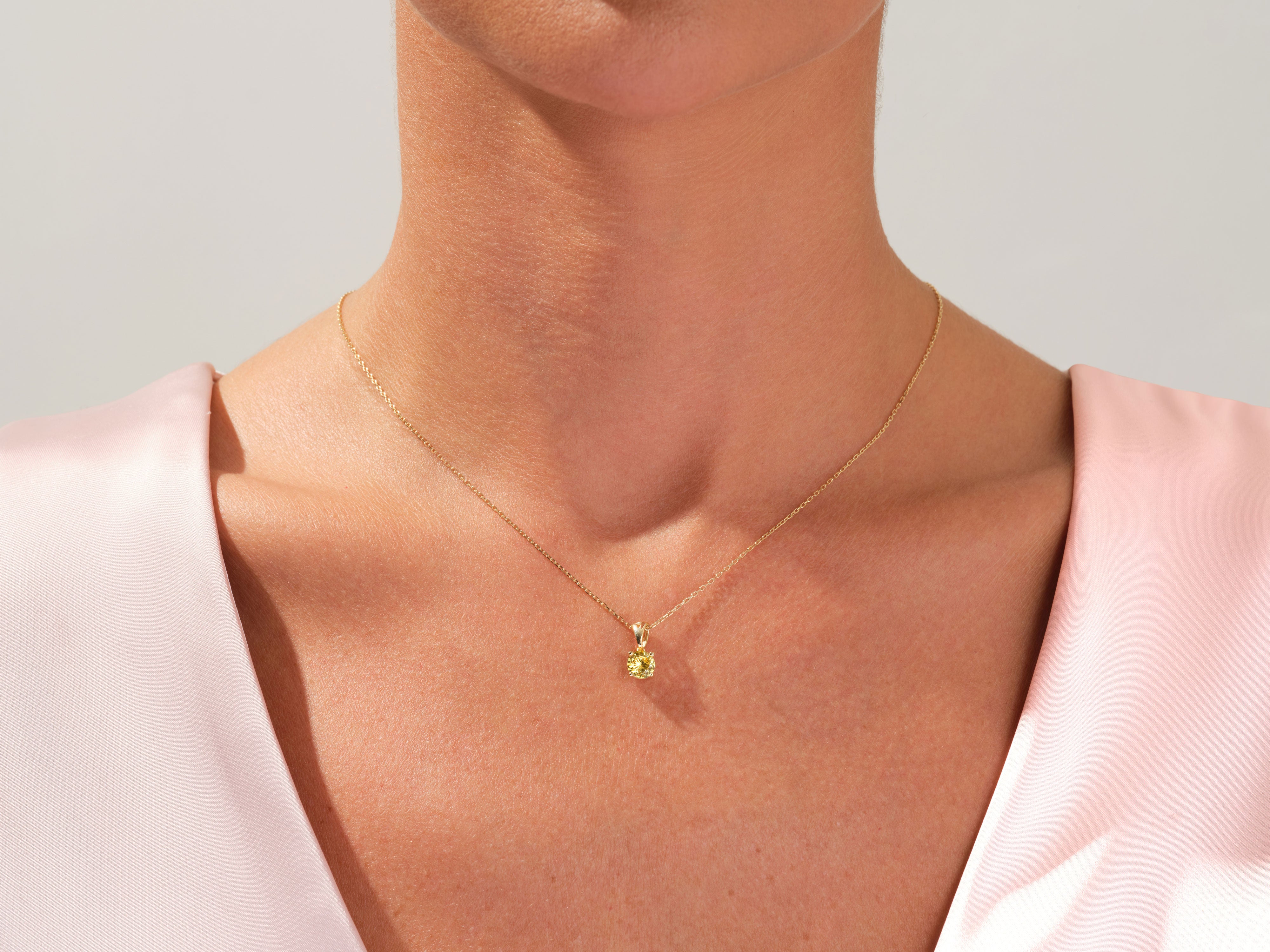 Gold necklace with yellow gemstone pendant on a woman's neck