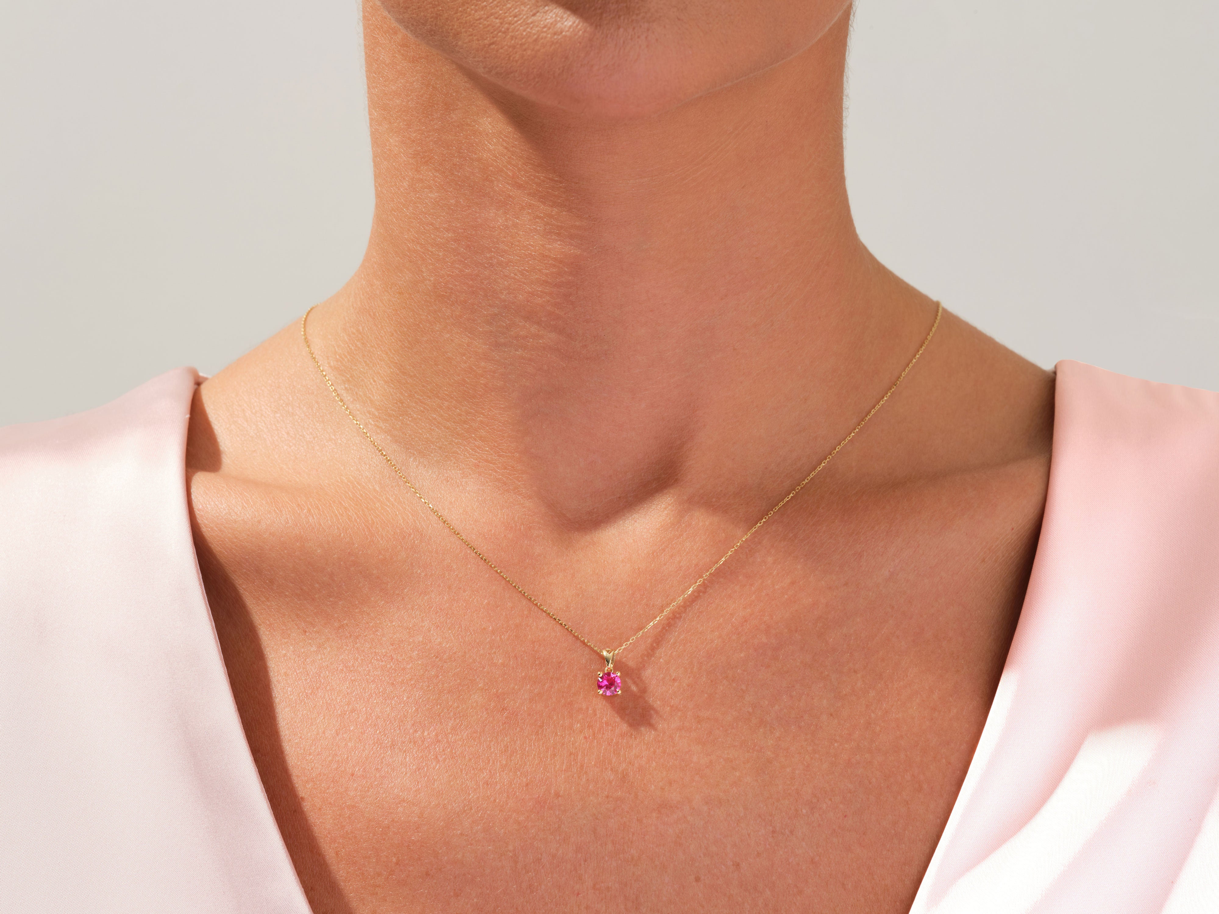 Gold necklace with pink gemstone pendant on woman's neck