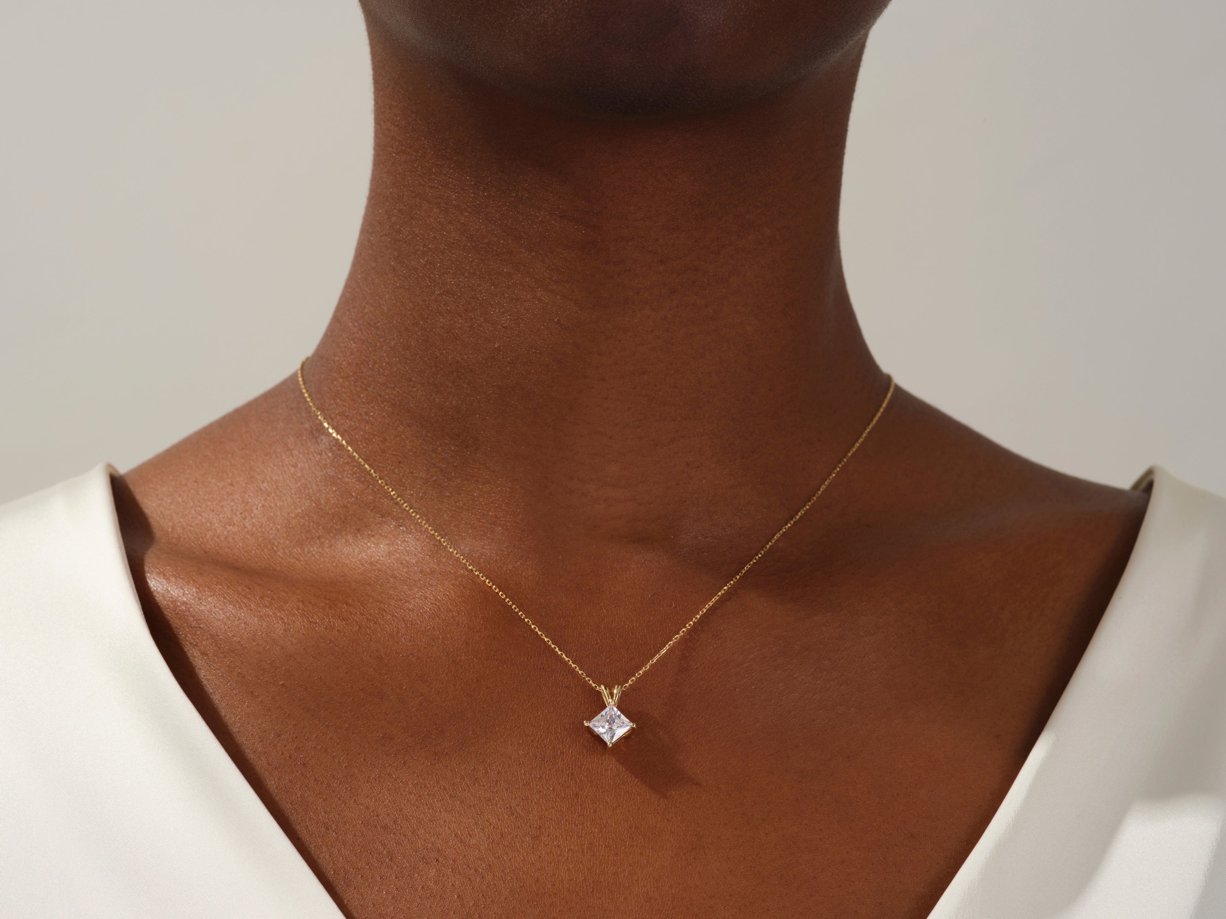 Gold necklace with princess cut diamond pendant on model