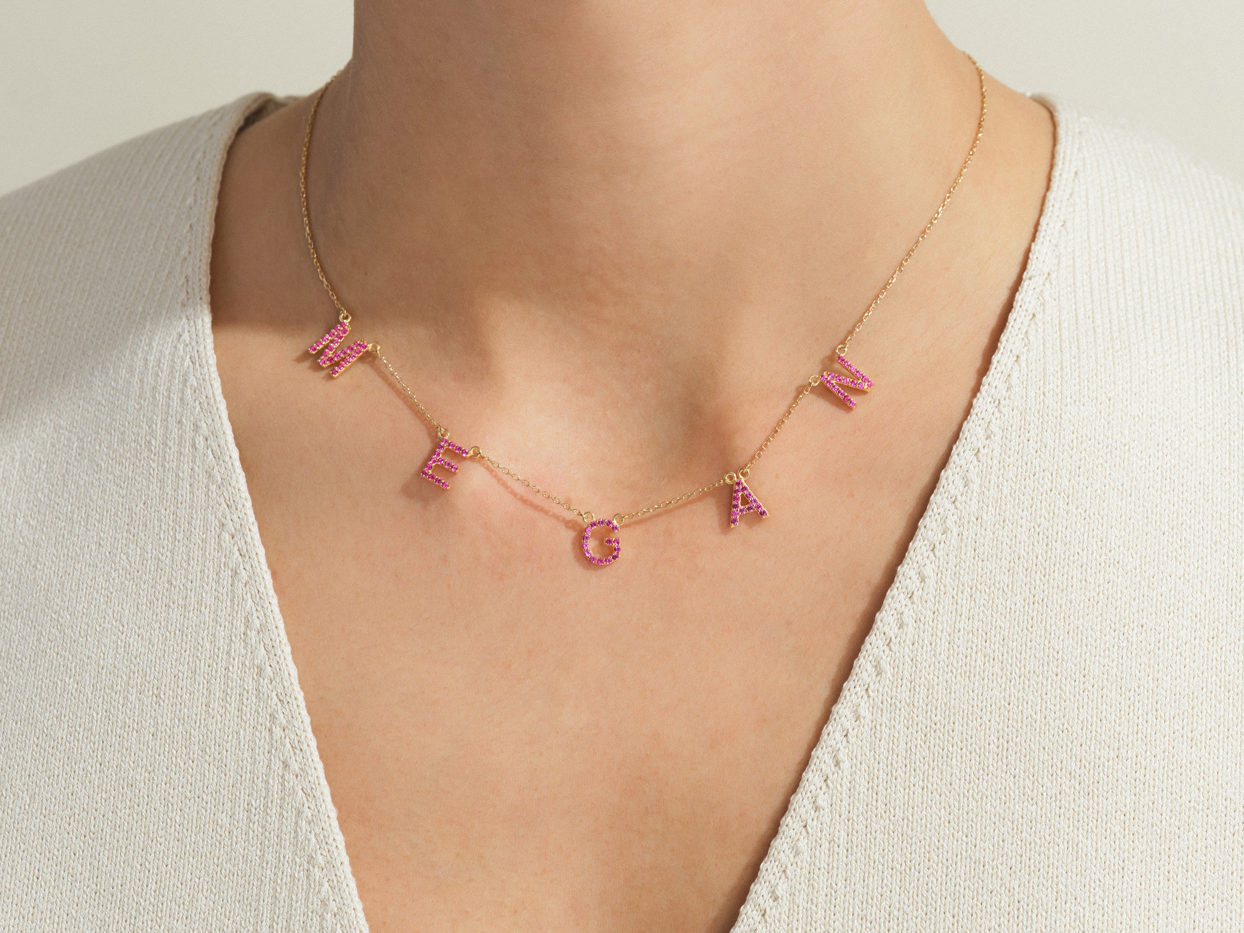 Gold necklace with pink gem letters spelling "MEGAN"