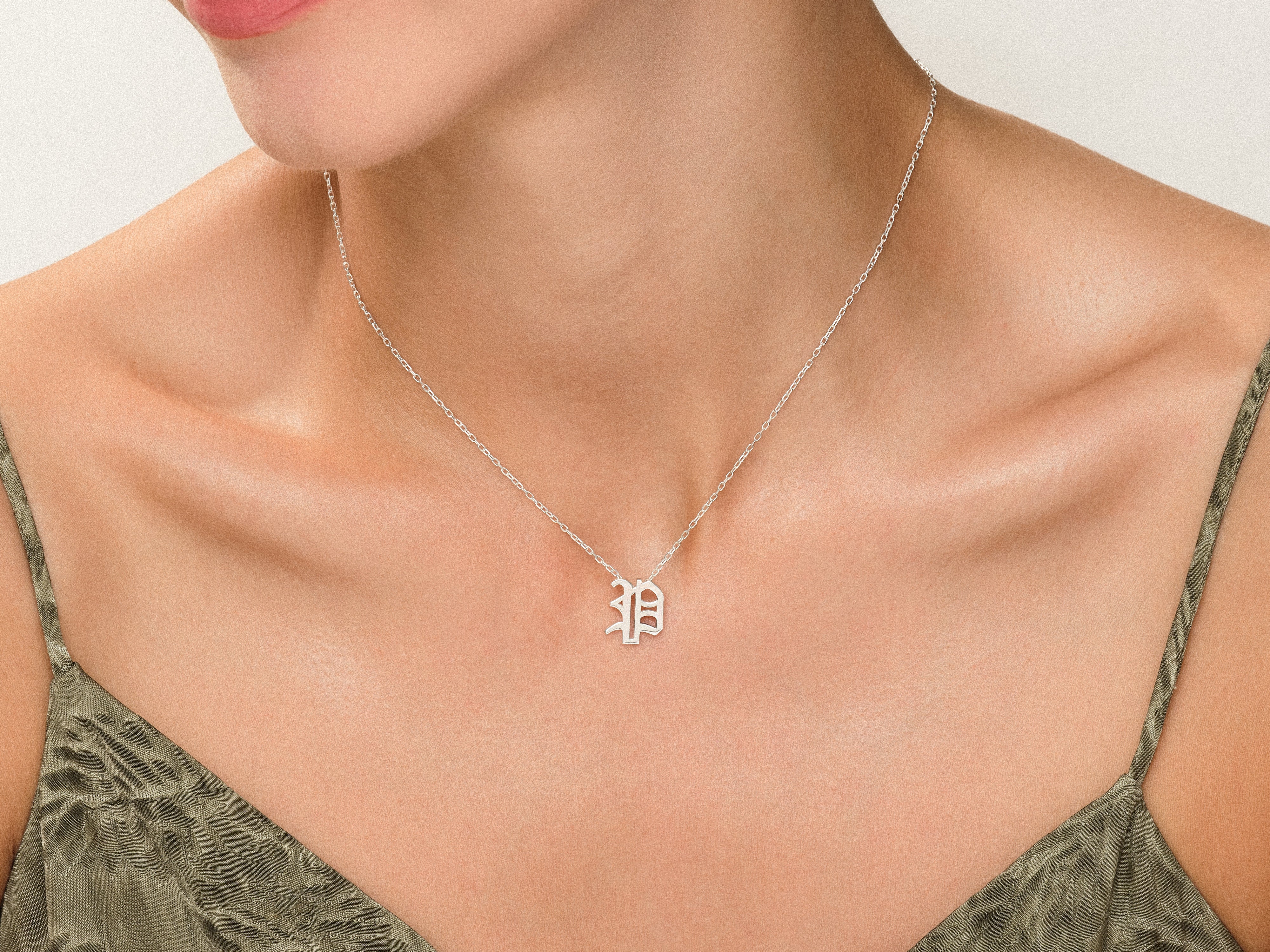 Silver gothic initial necklace on a woman's neck