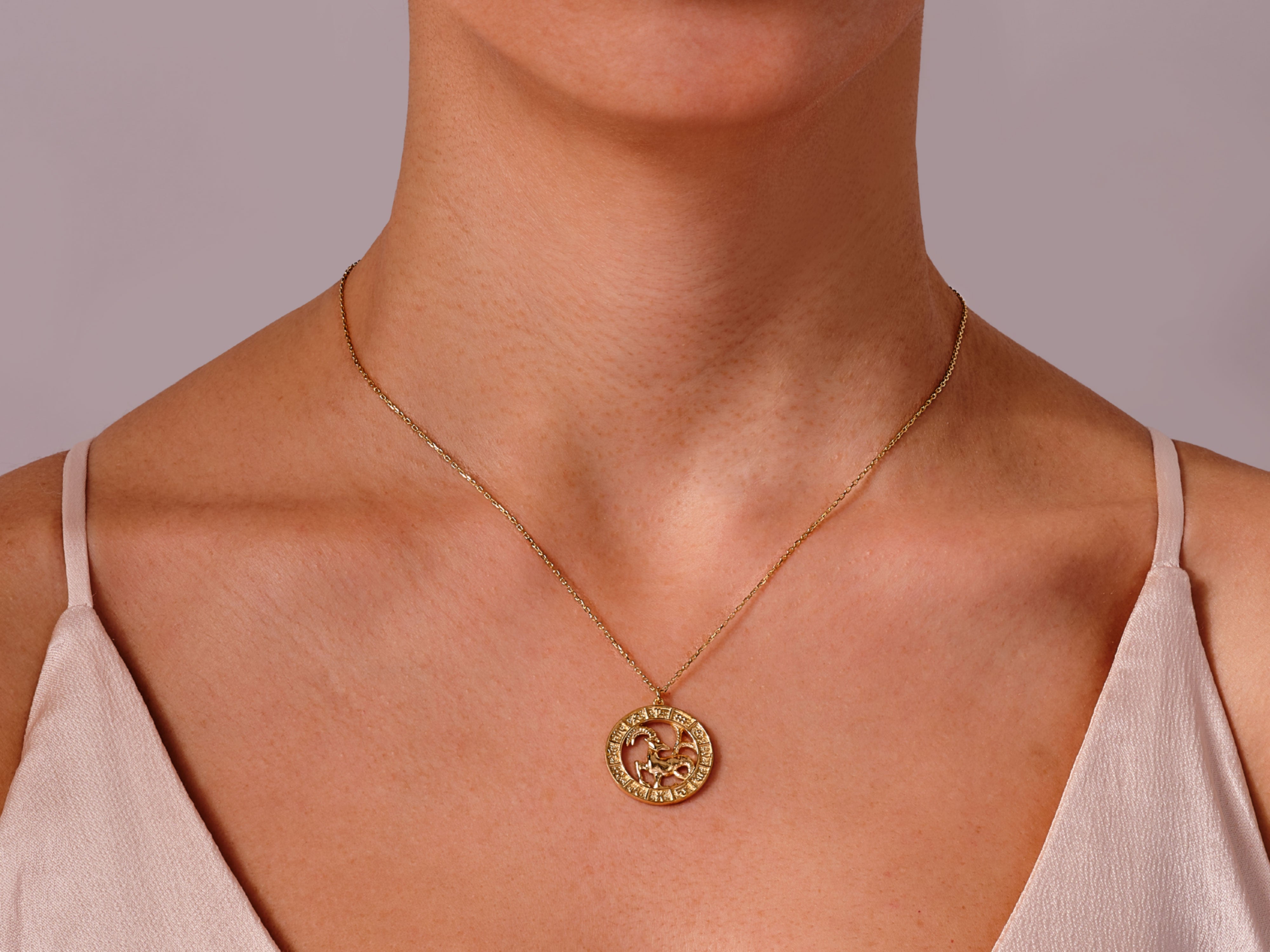 Gold Capricorn zodiac necklace on a woman's neck