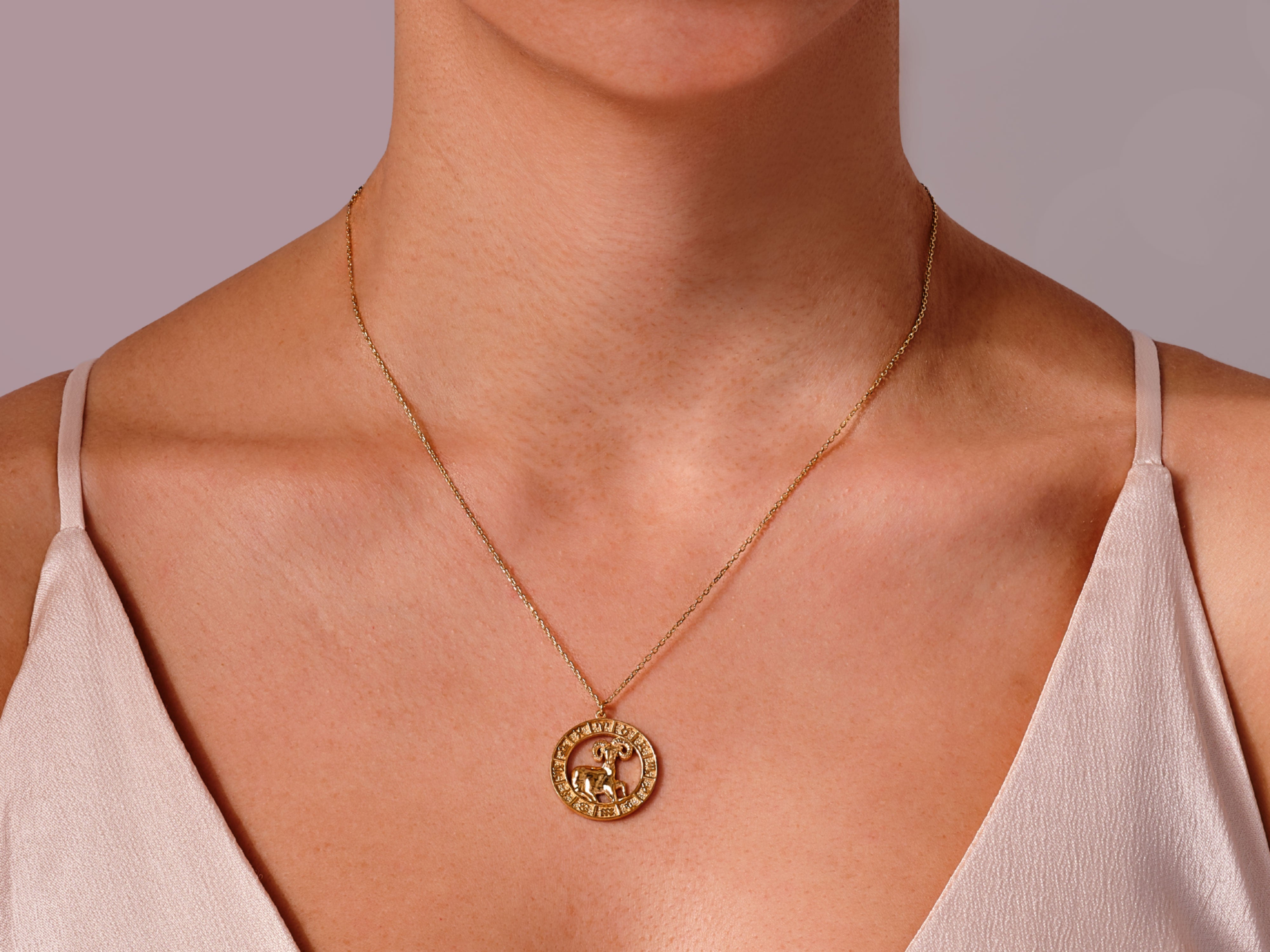 Gold Aries zodiac necklace on a woman's neck