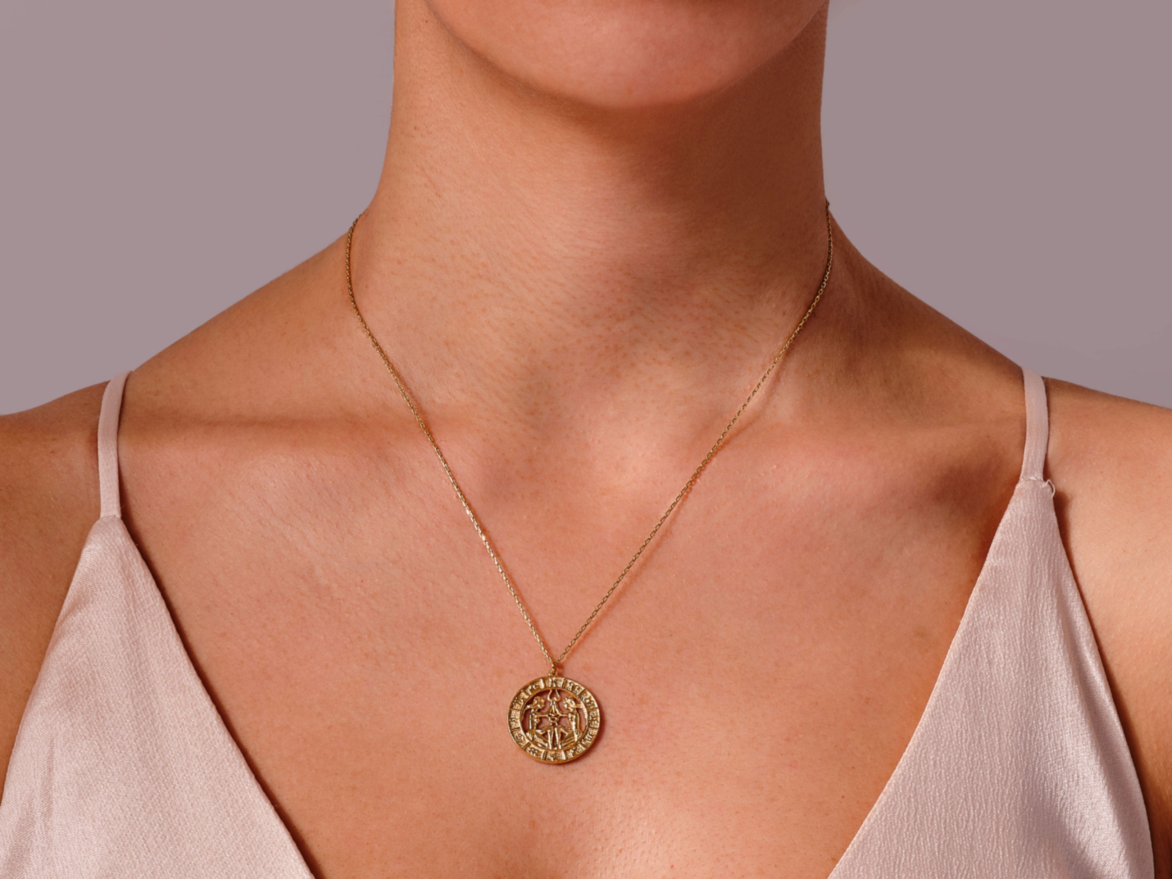 Gold zodiac pendant necklace on a woman's neck