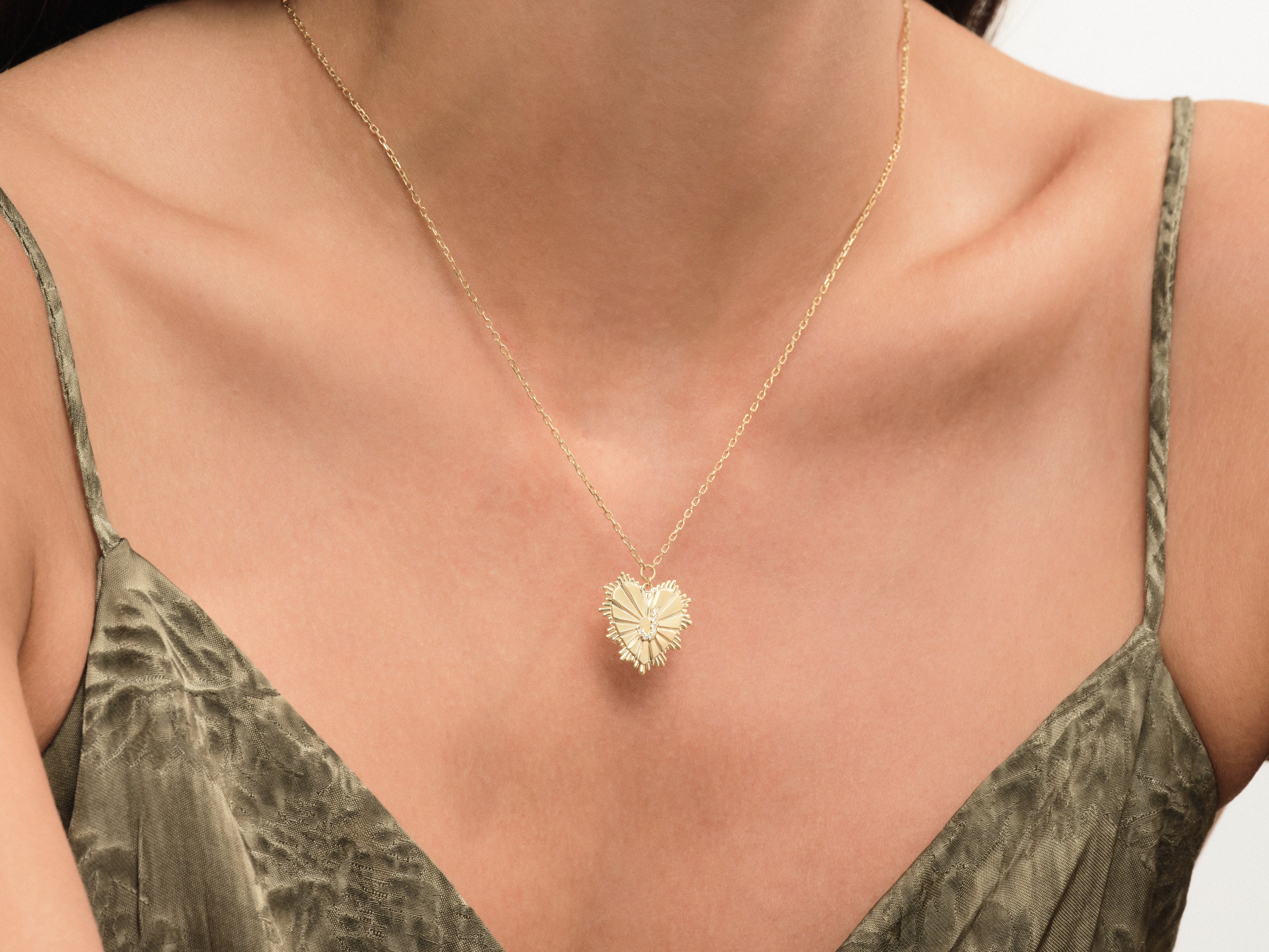 Gold heart pendant necklace with diamonds on a woman's décolletage