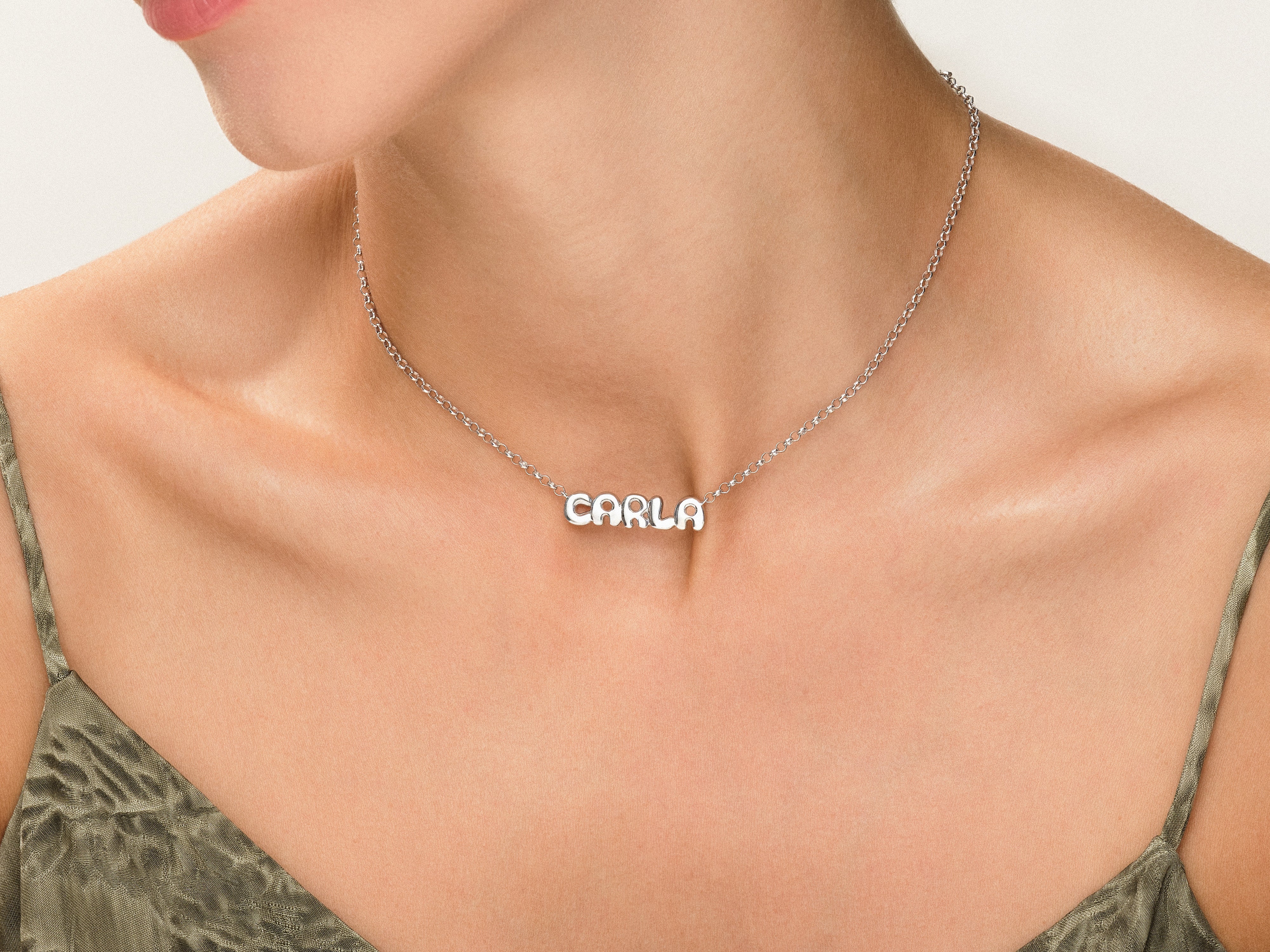 Silver 'CARLA' name necklace on a woman's neck