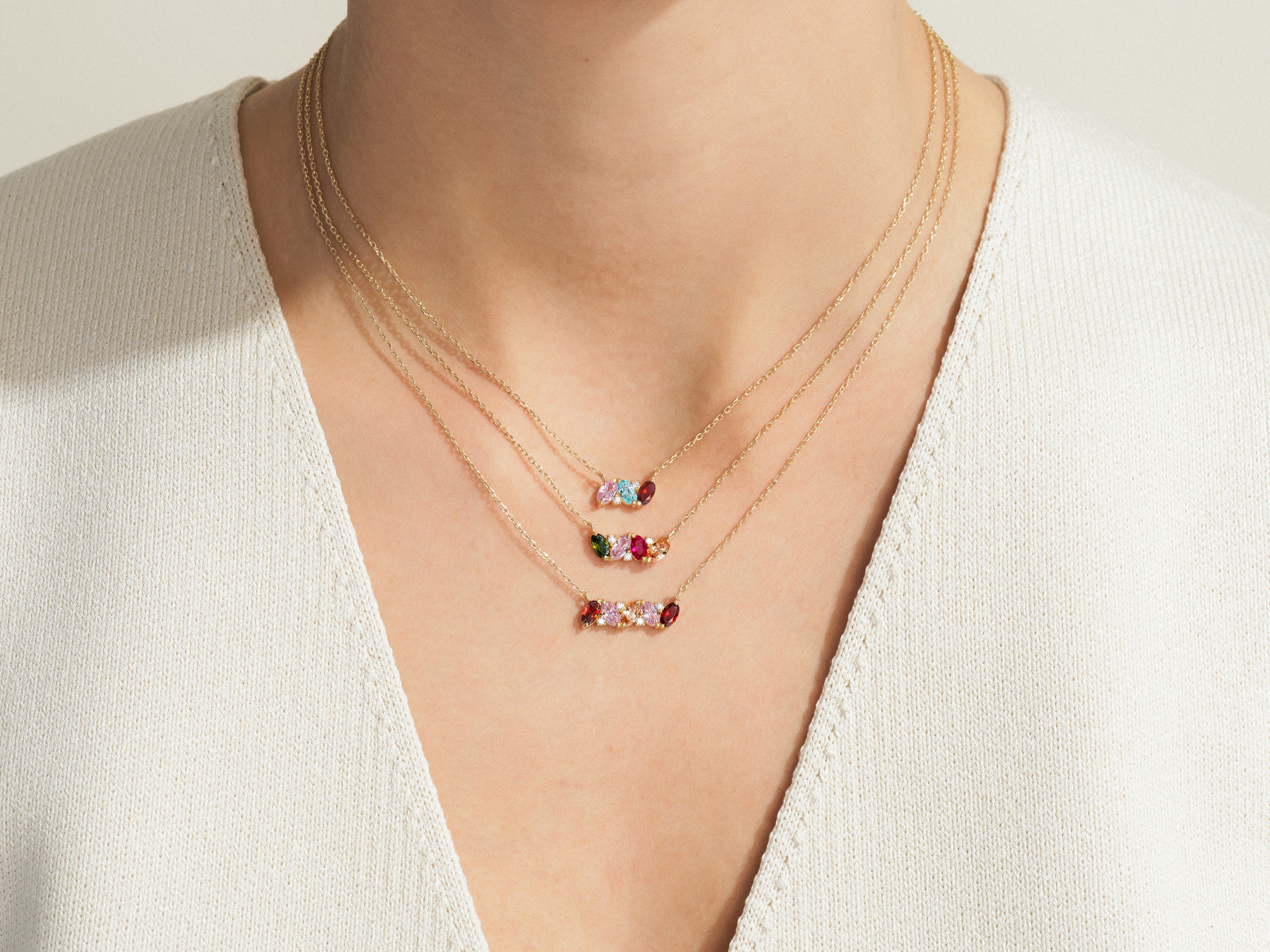 Gold necklaces with colorful gemstone pendants on a person's neck