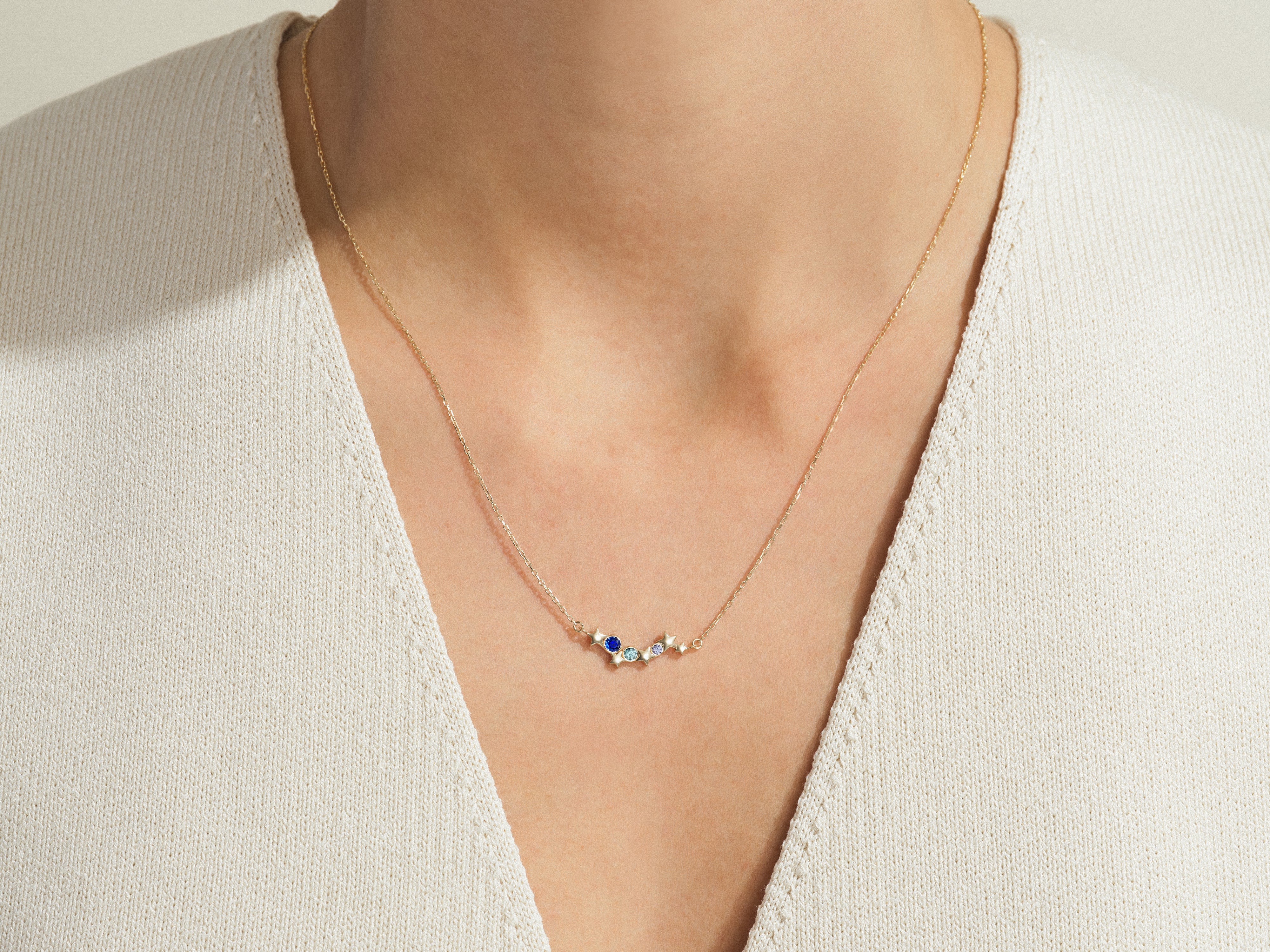 Gold necklace with blue and diamond star charms on a woman's neck