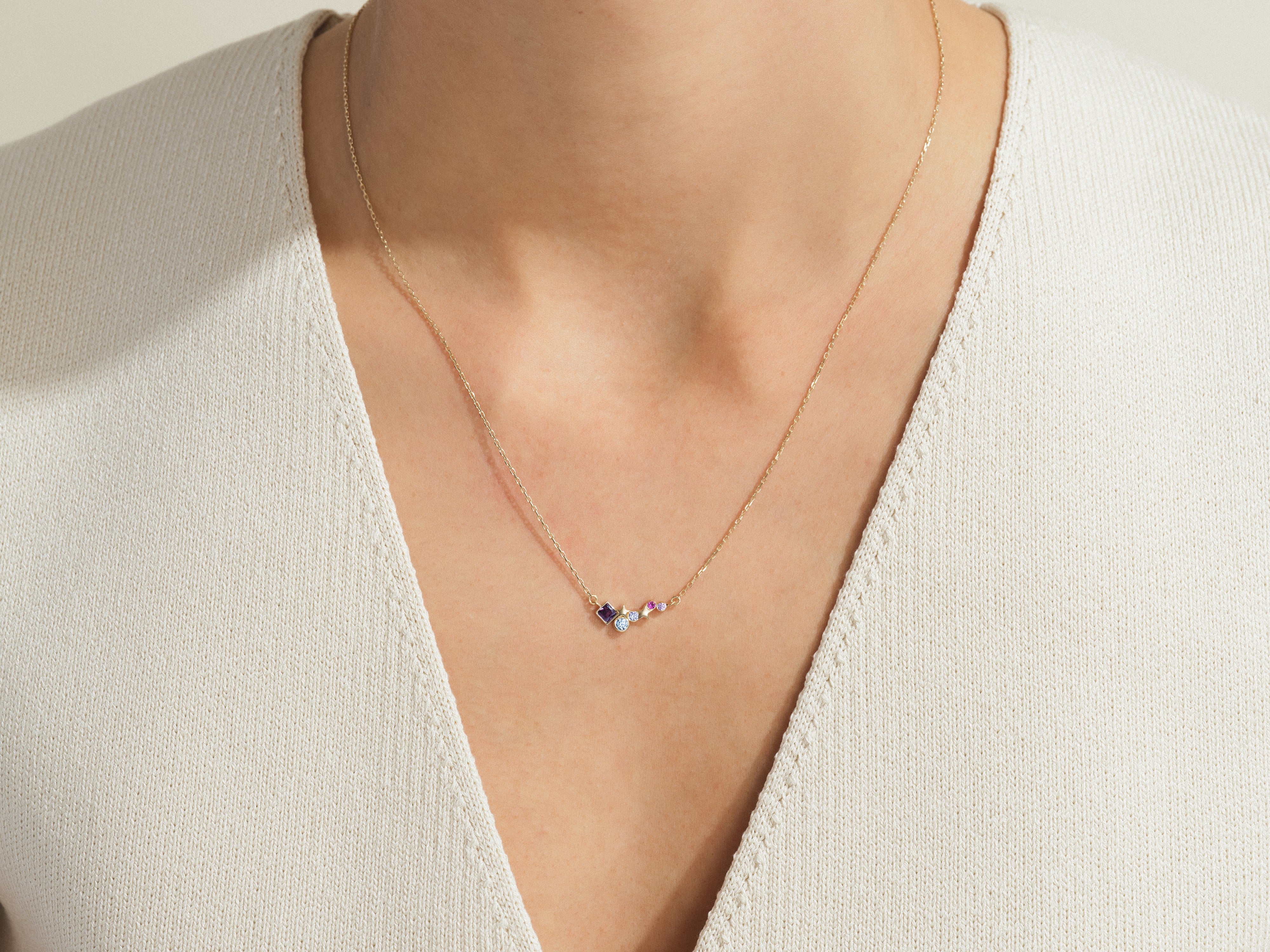 Gold necklace with colorful gemstone charms on a woman's neck