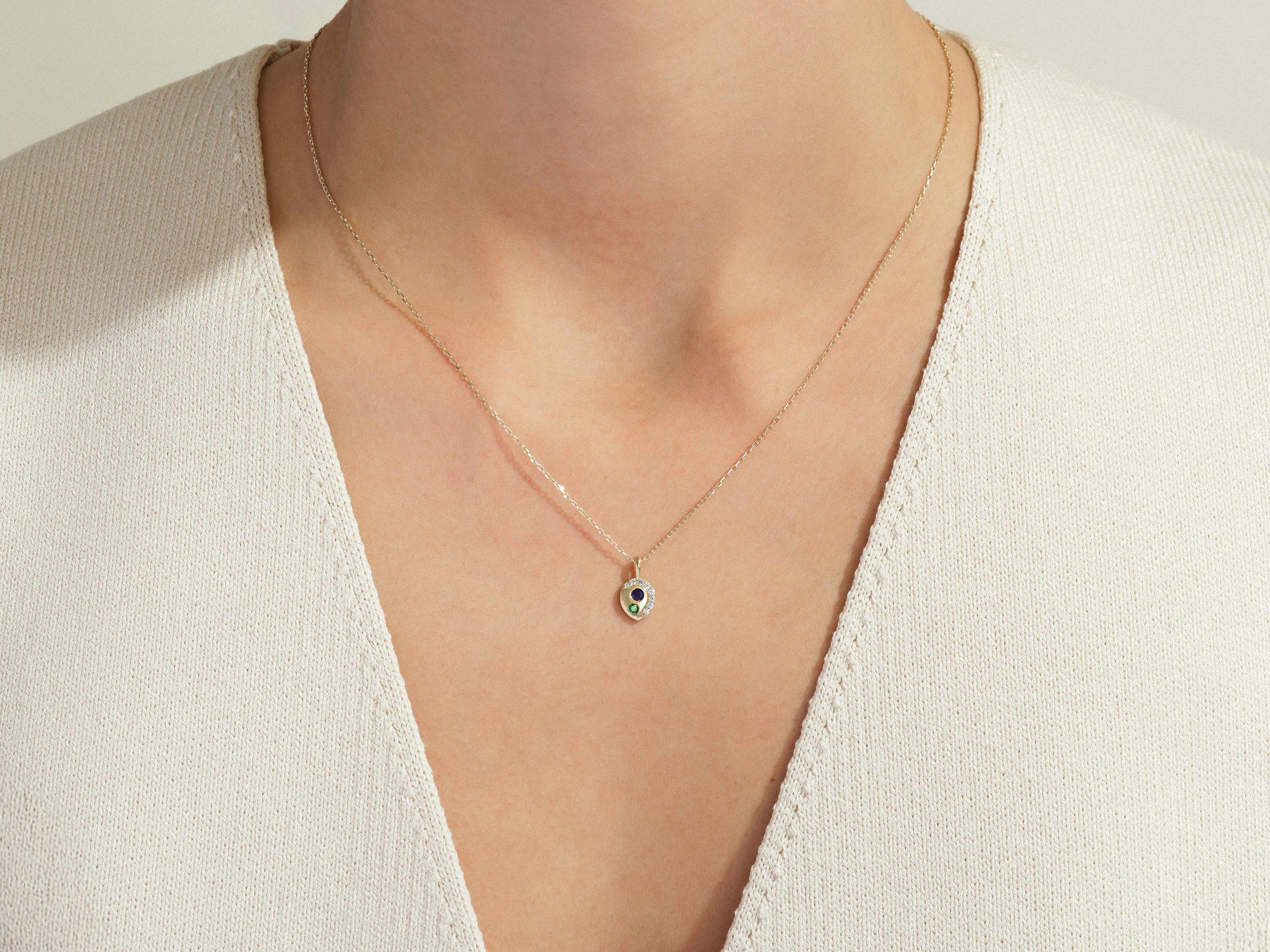 Gold necklace with heart pendant, featuring gemstones