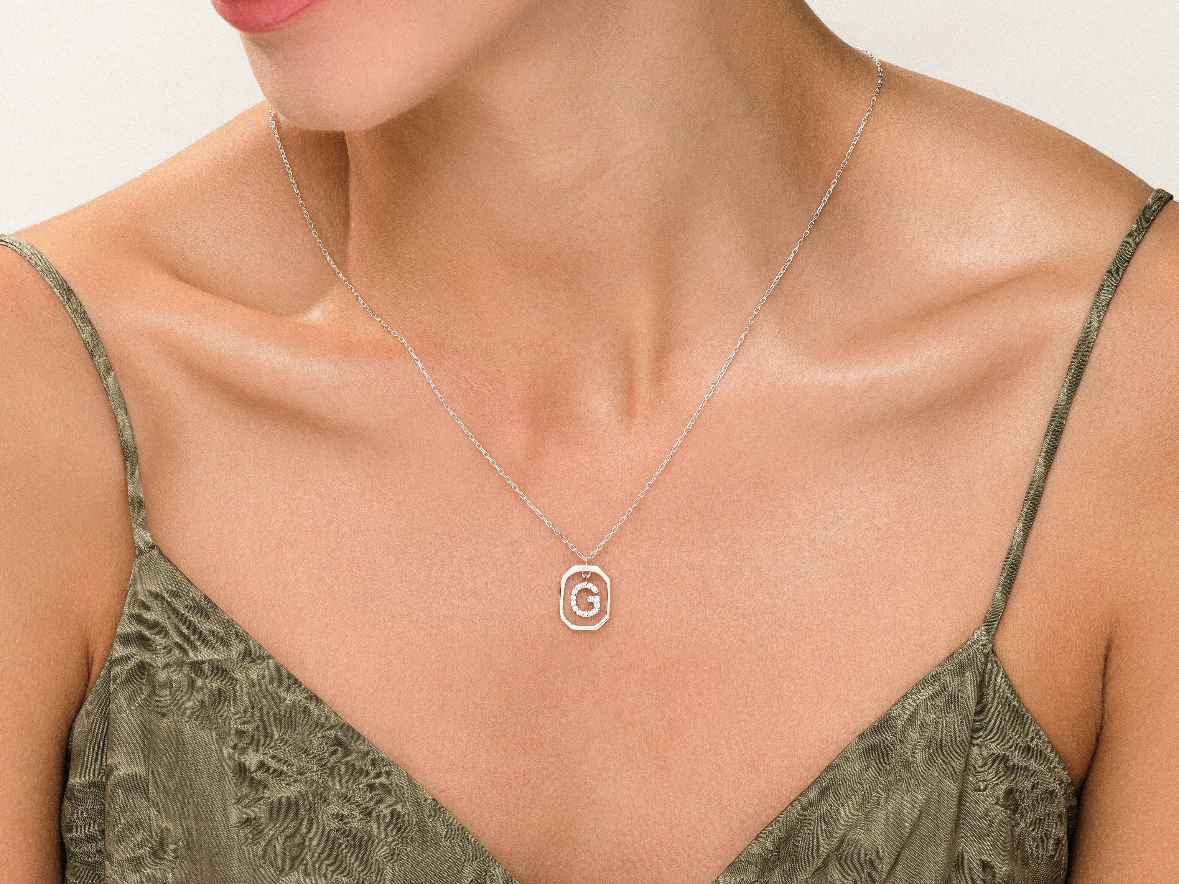 Diamond initial 'G' necklace on a woman's neck
