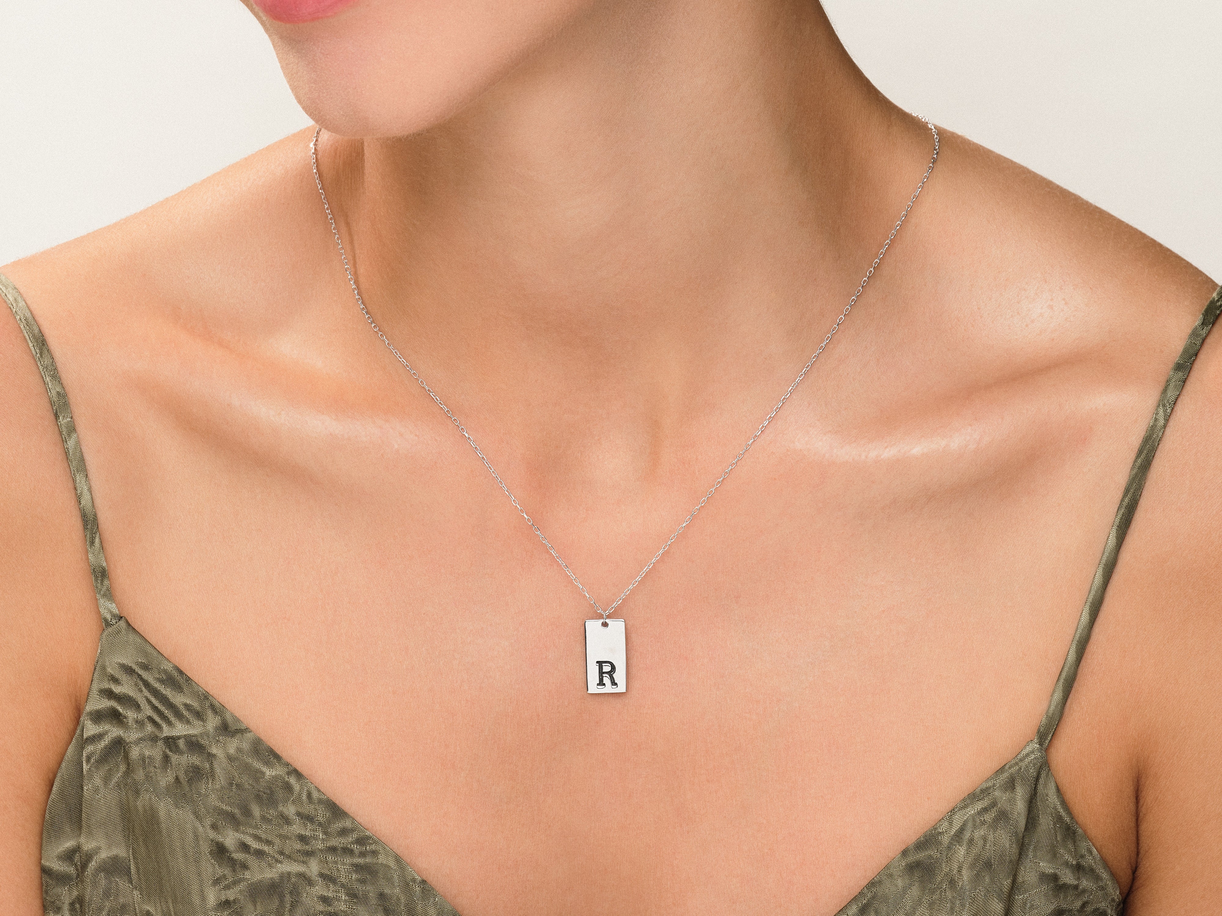 Silver initial R necklace on a woman's neck