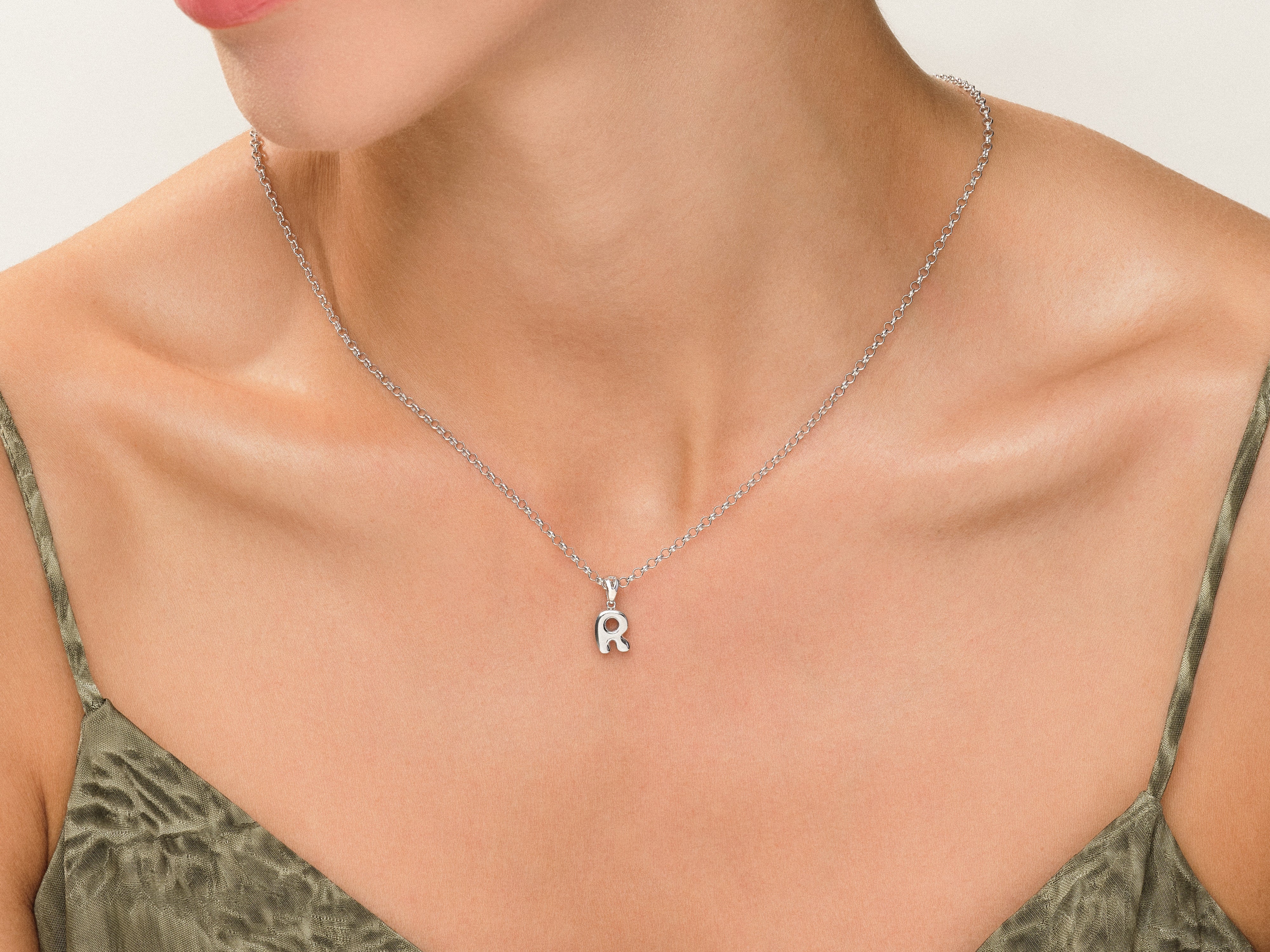 Silver initial 'R' pendant necklace on a woman's neck
