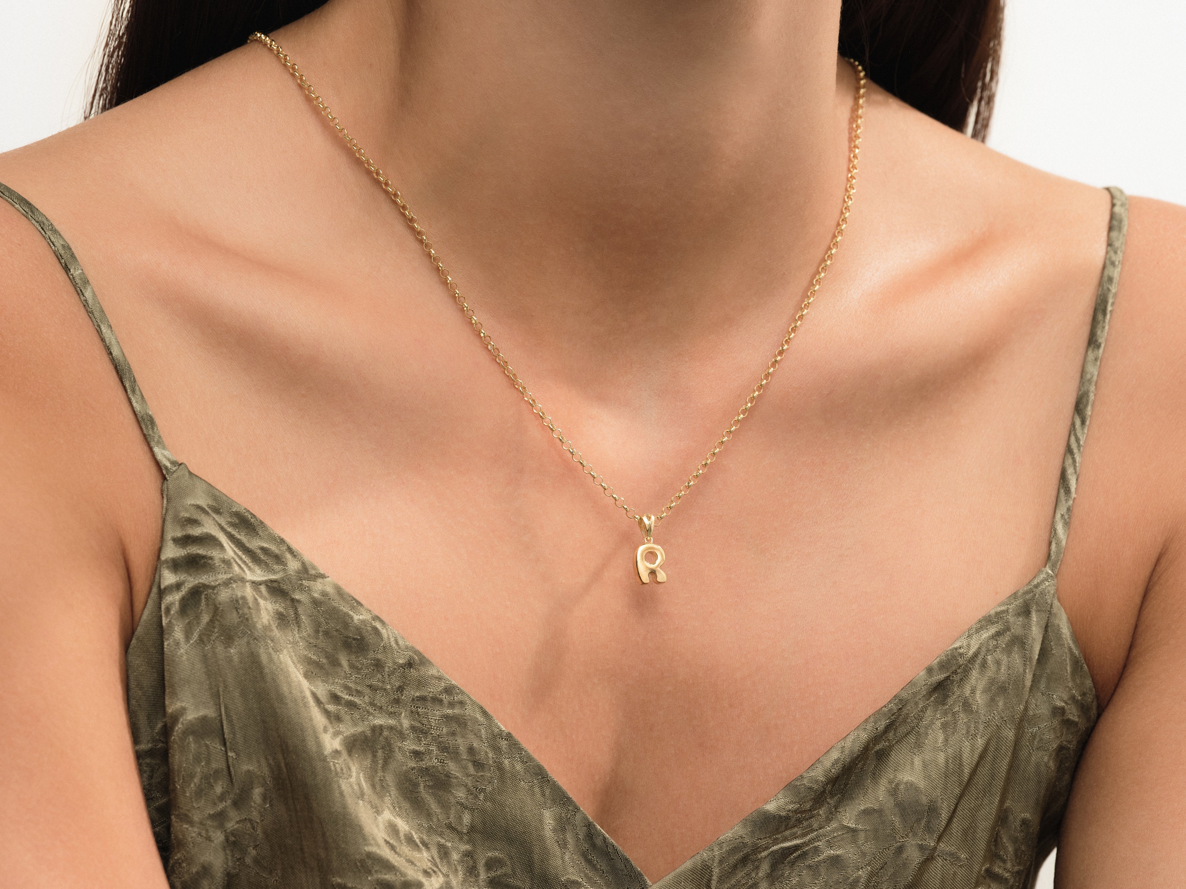 Gold letter R necklace on a woman's neck