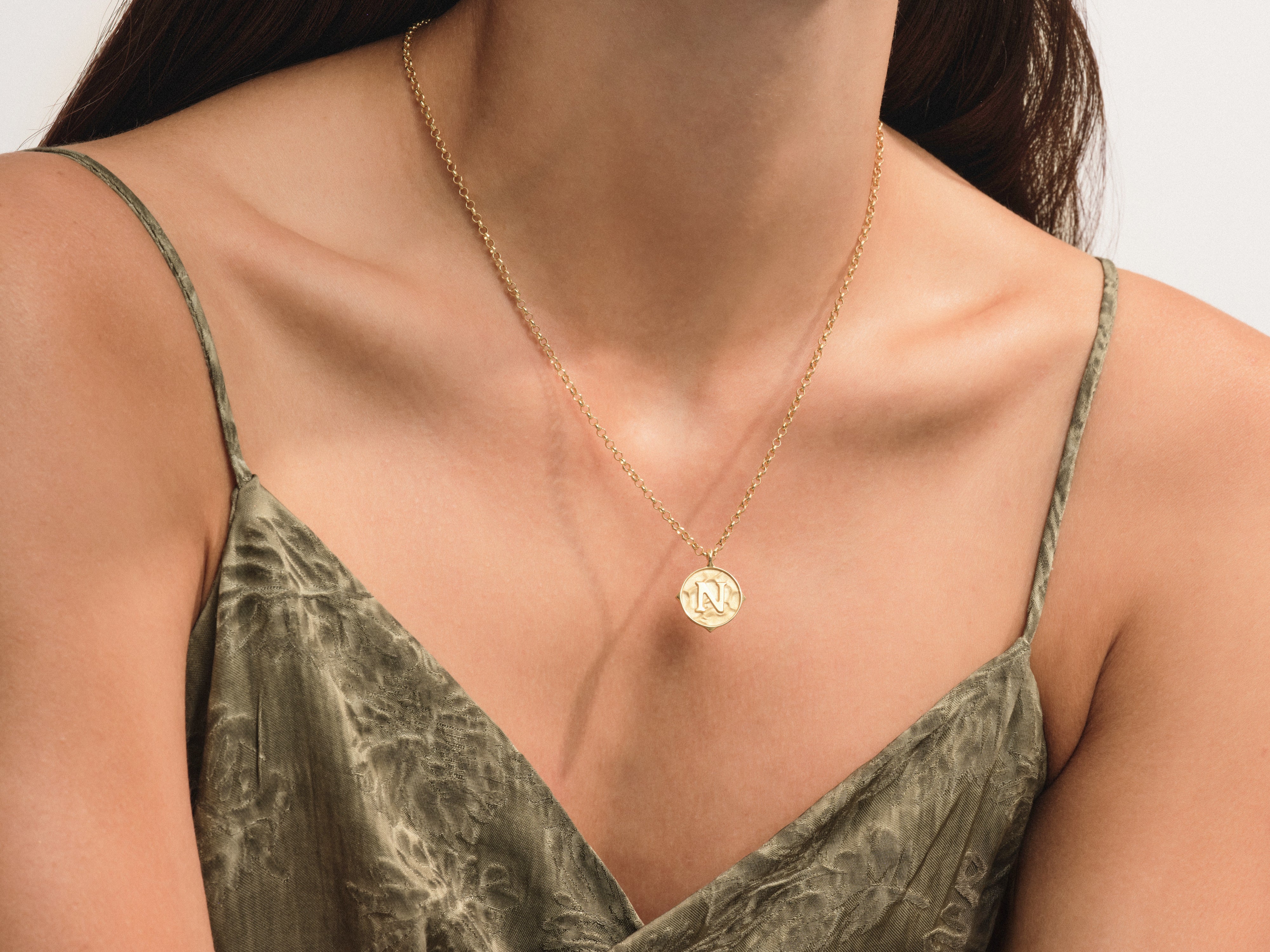 Gold initial necklace on a woman's décolletage