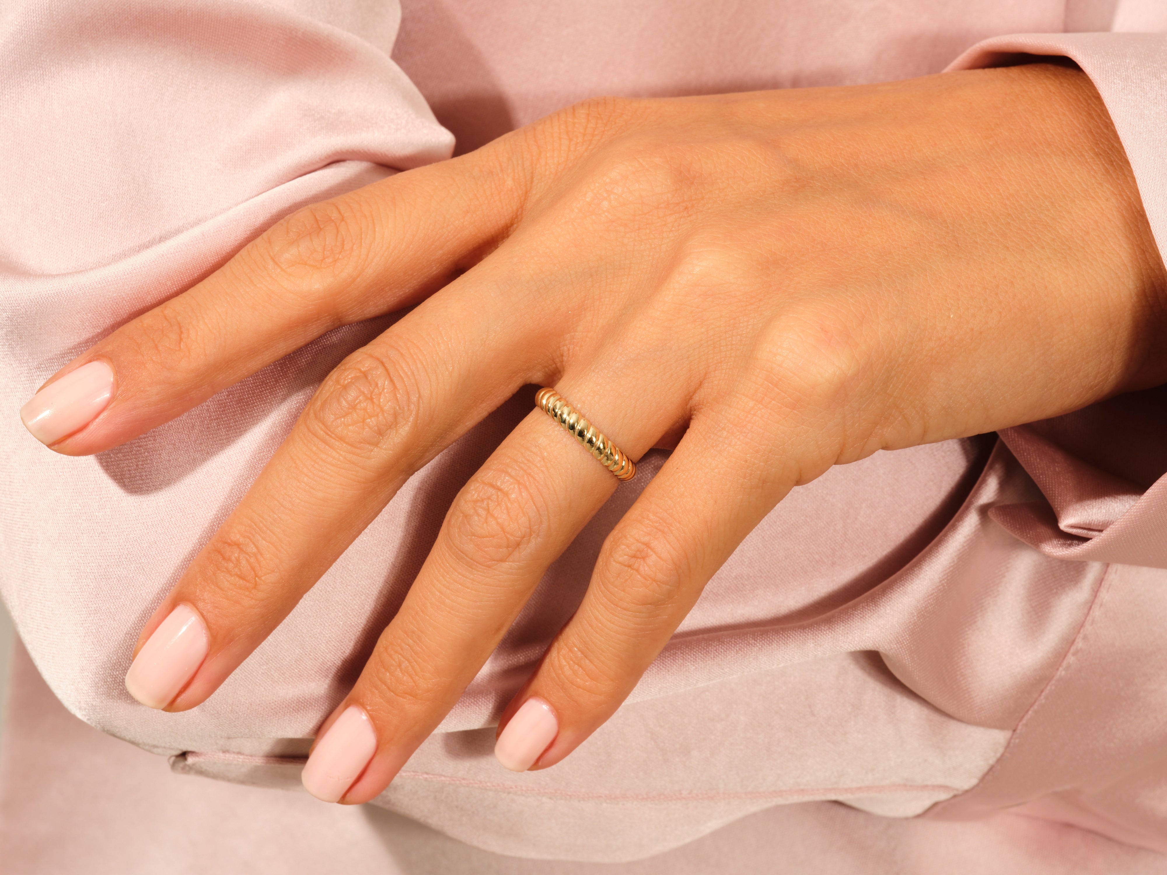 Gold twisted band ring on a woman's finger, jewelry product shot