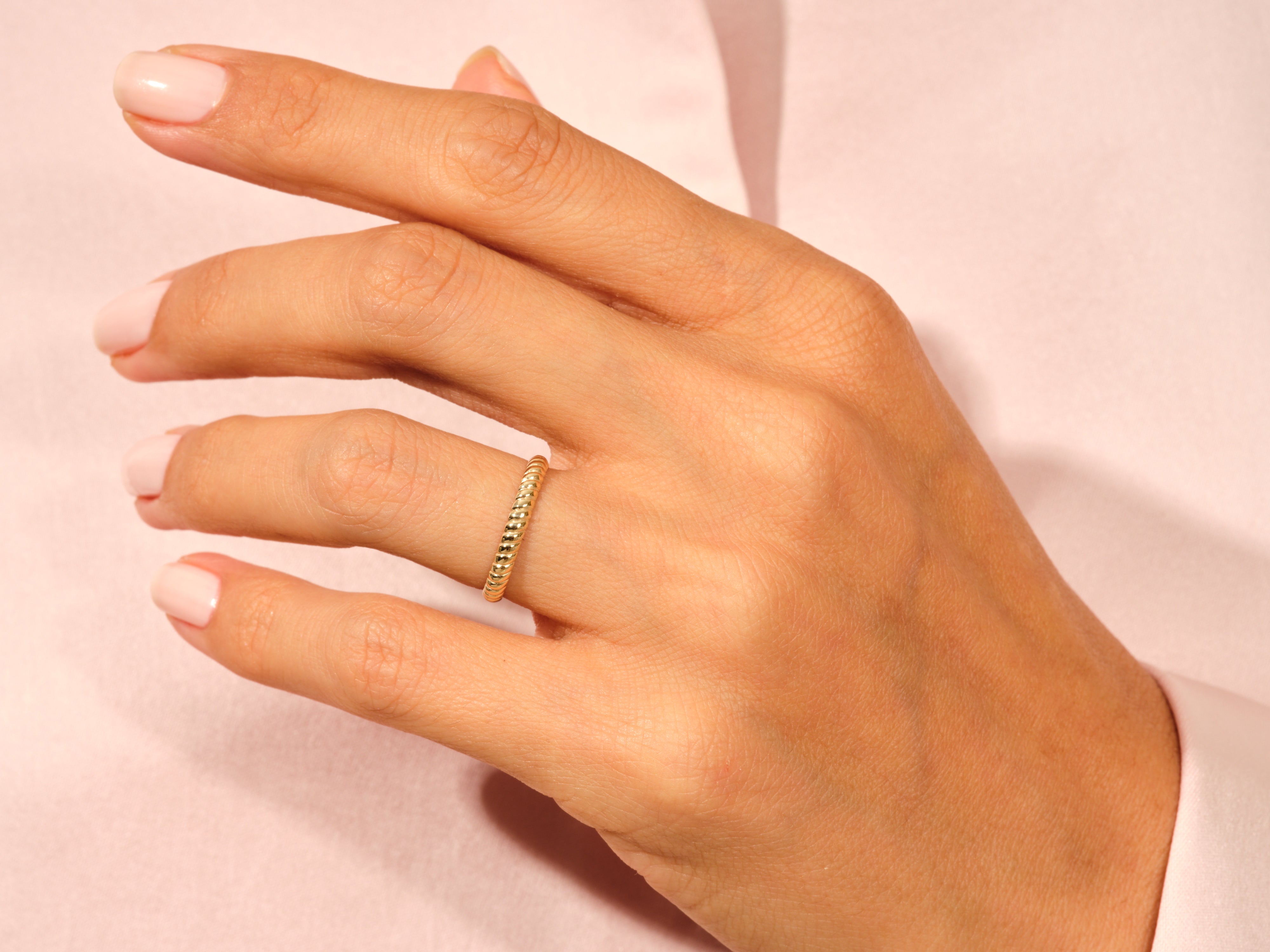 Gold twisted band ring on a woman's finger, jewelry