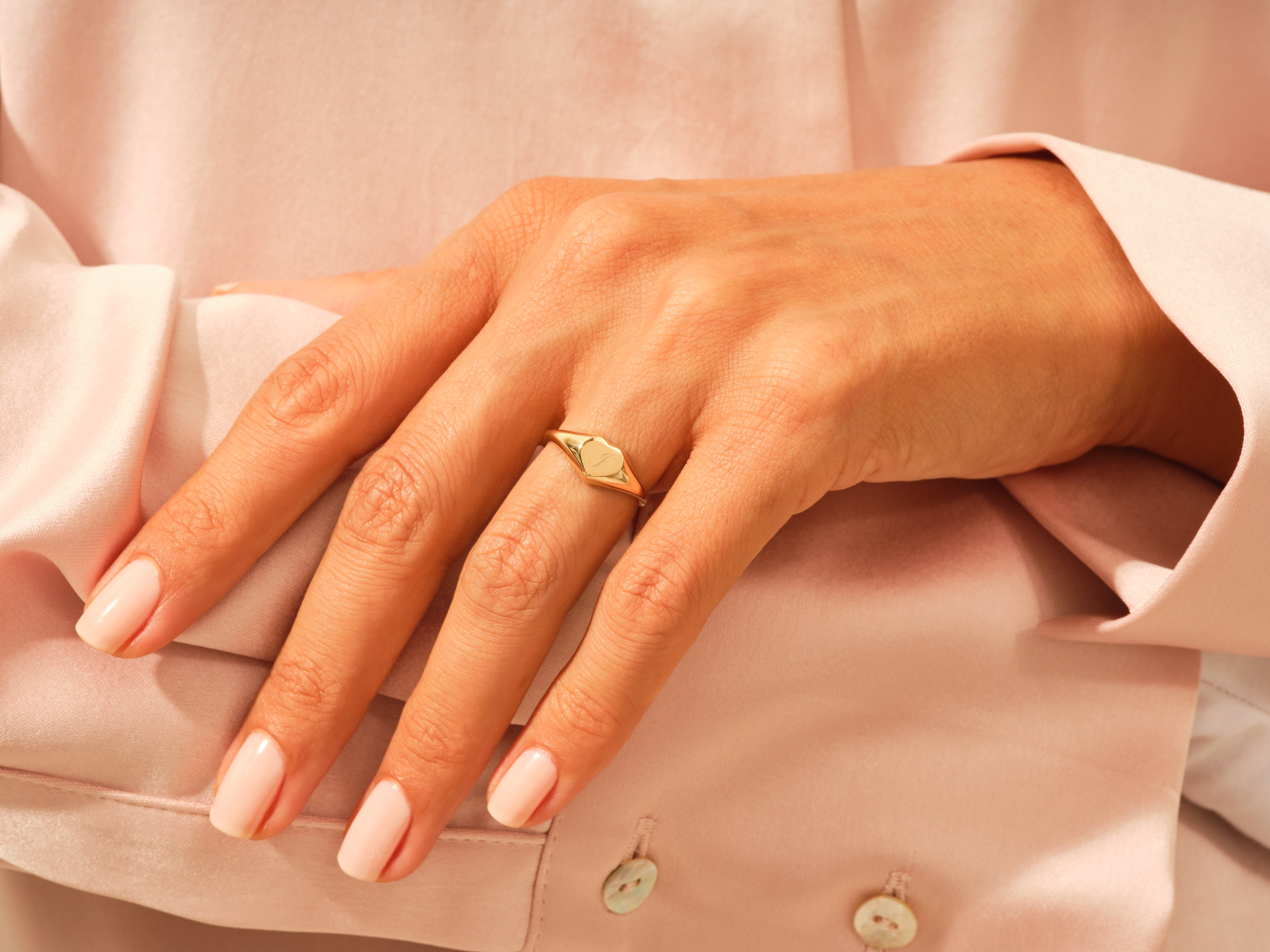 Gold heart signet ring on a hand, jewelry for women