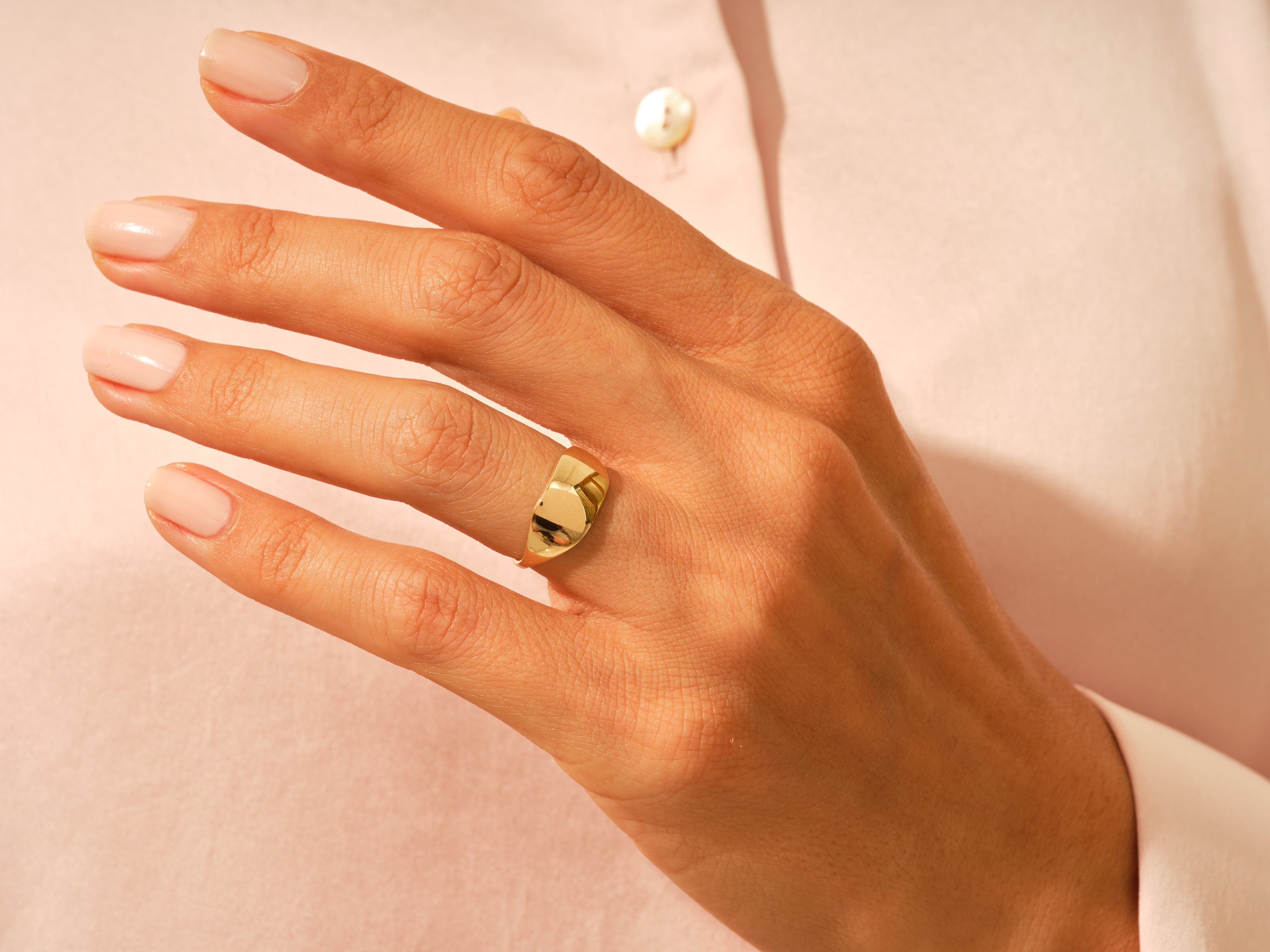 Gold signet ring on a woman's finger, jewelry product photography
