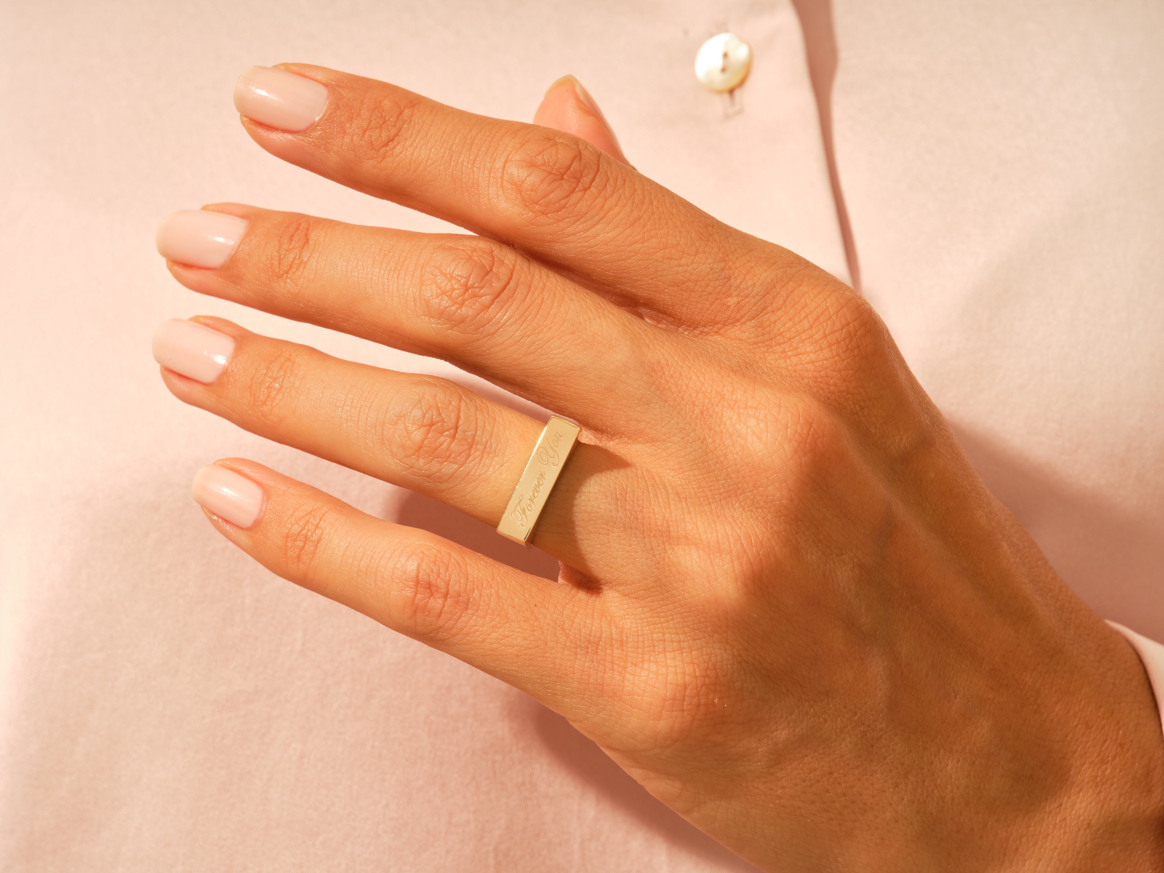 Gold bar ring with "Forever You" engraving on a woman's hand