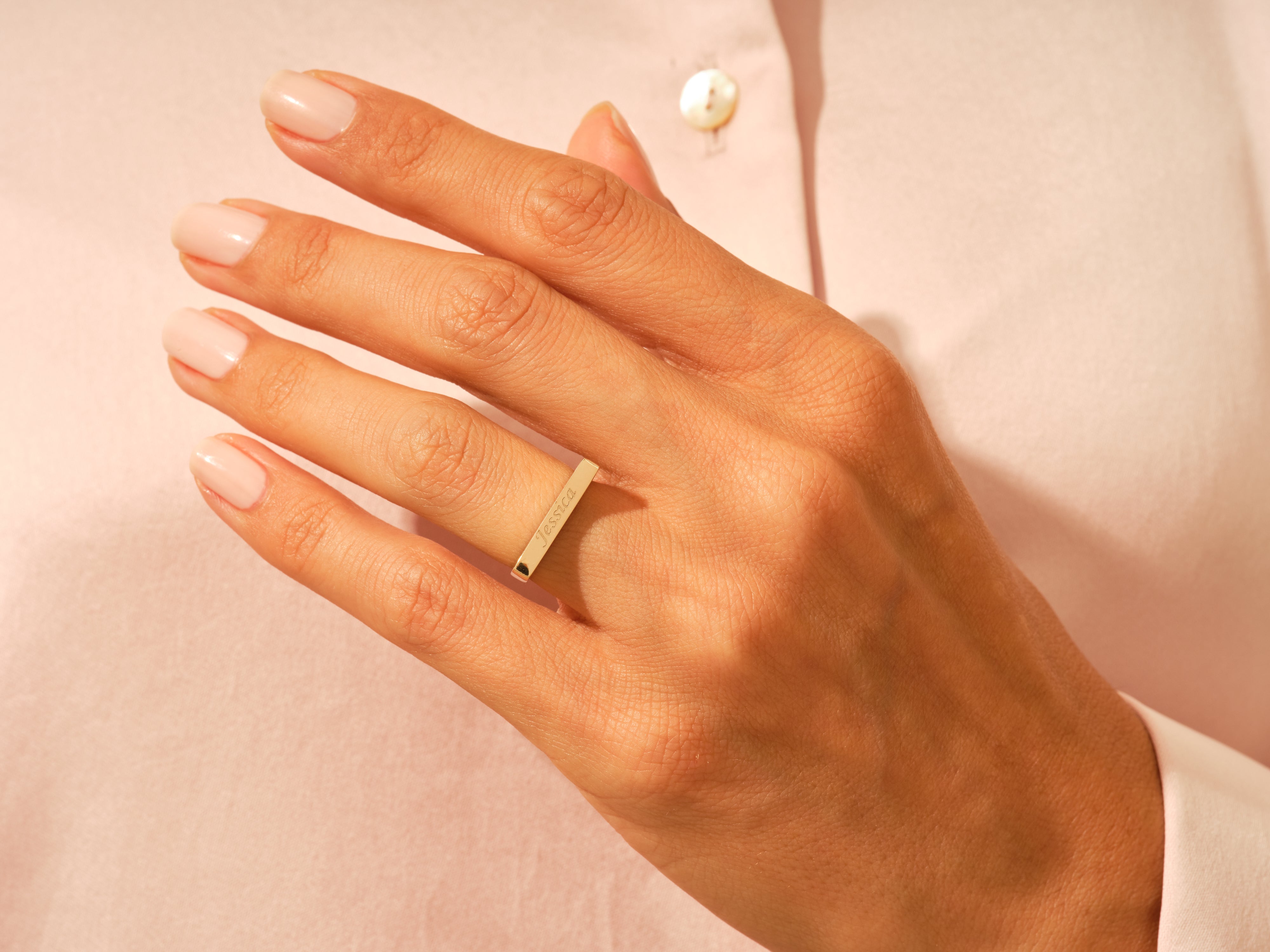 Gold bar ring with "Jessica" engraving on a woman's finger