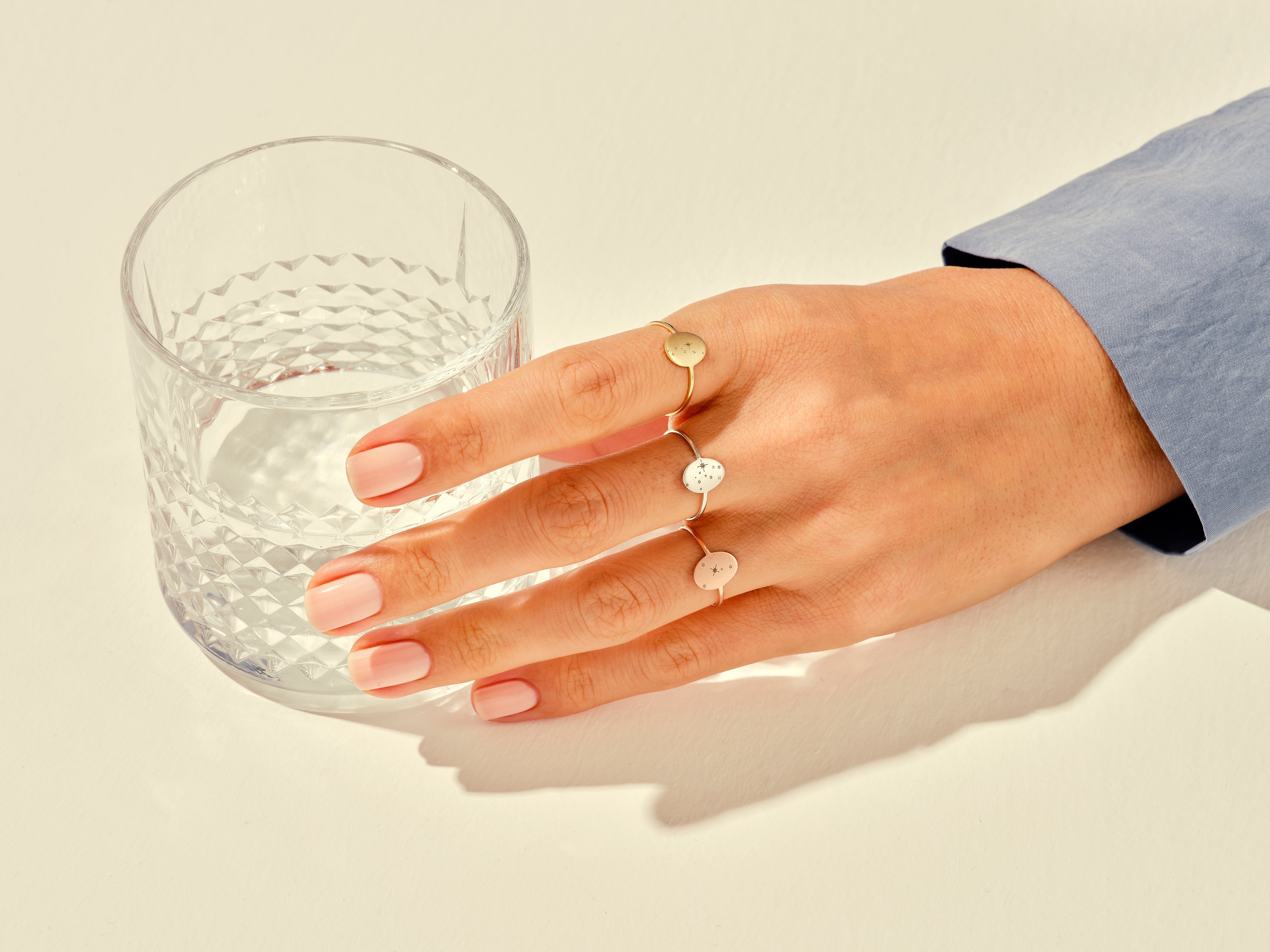 Delicate oval rings on hand next to glass of water