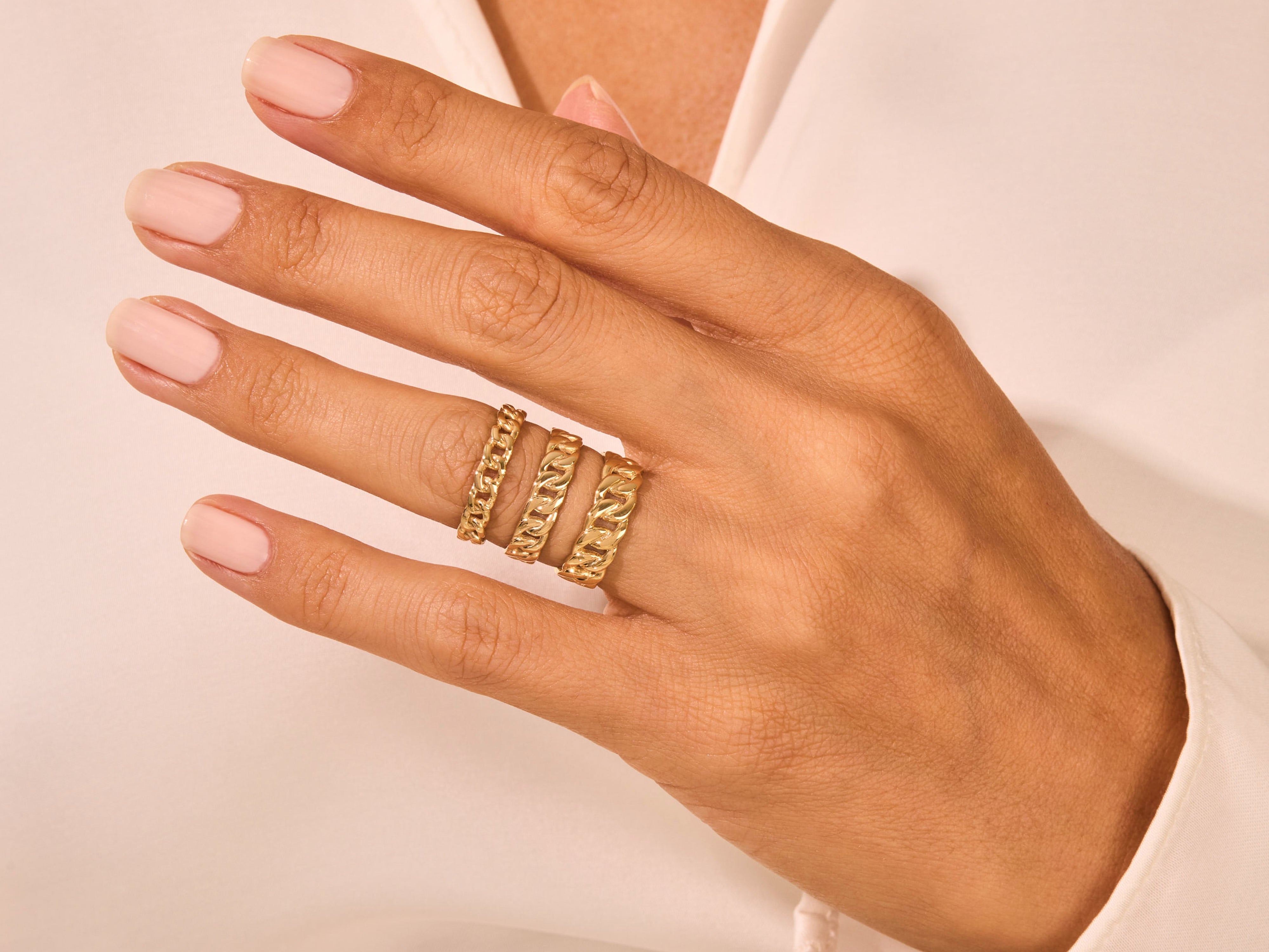 Gold curb chain rings stacked on a hand, fine jewelry