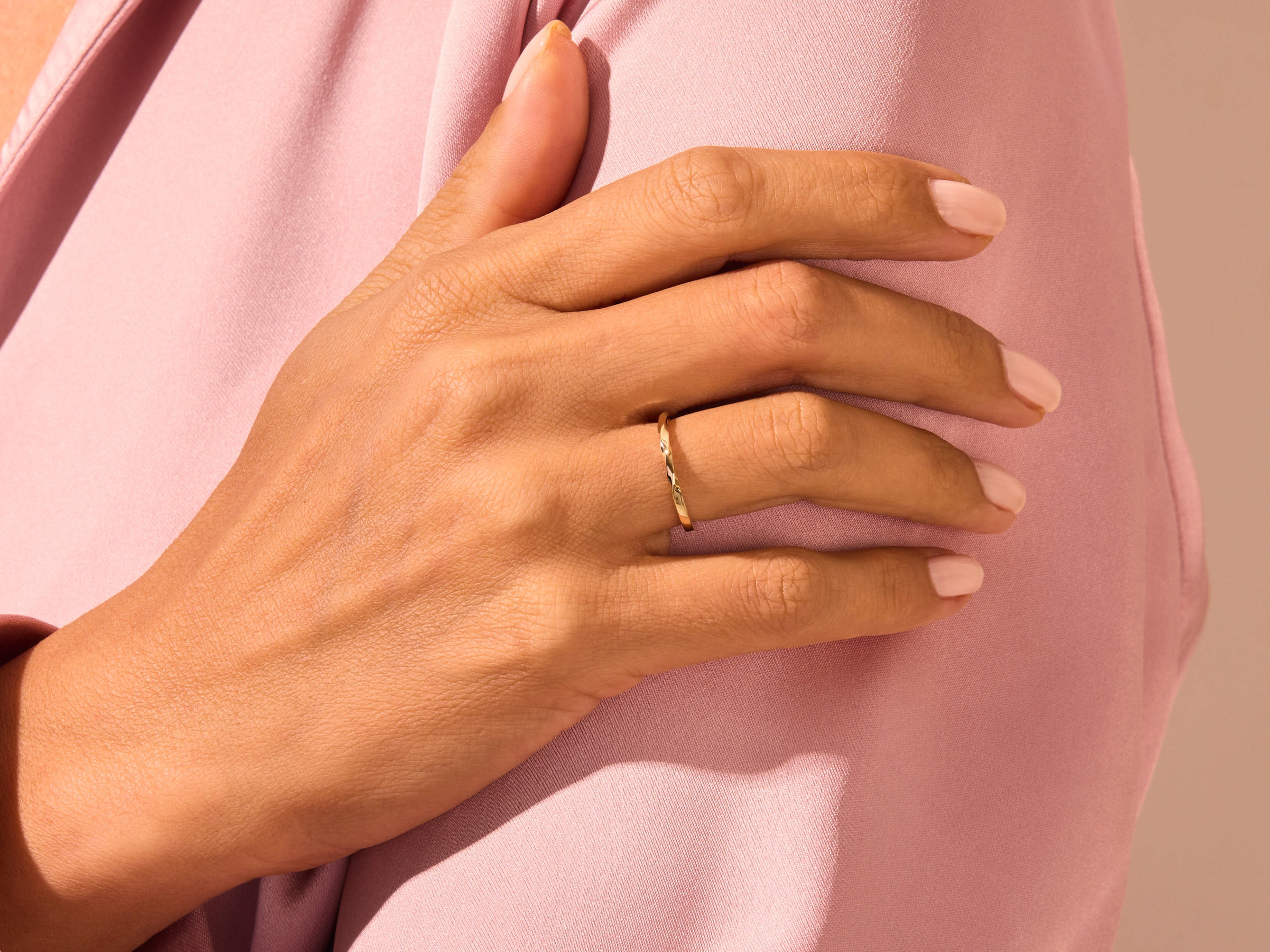 Delicate gold twisted ring on a hand, jewelry product shot