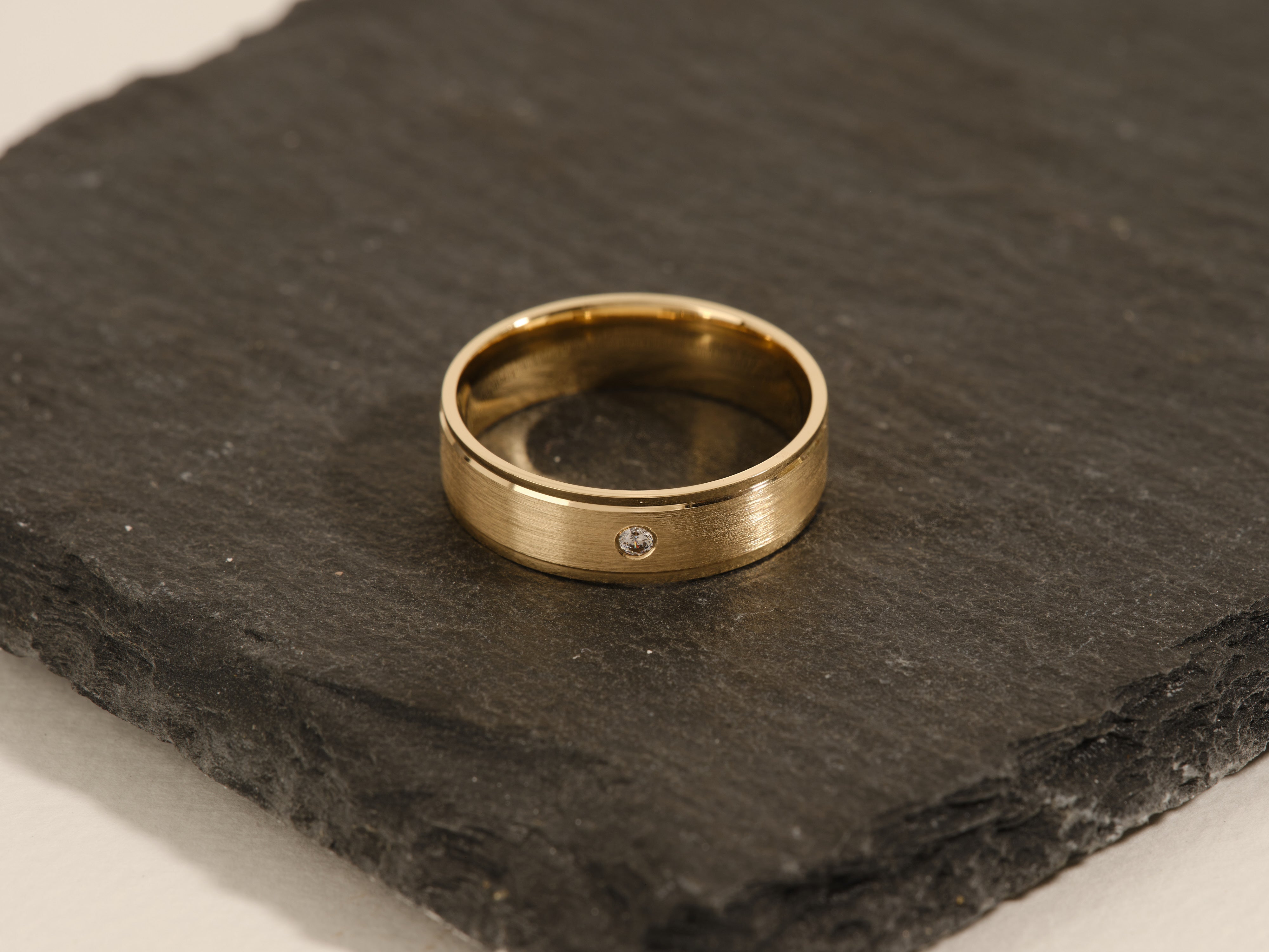 Gold ring with diamond accent on slate surface