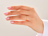 Gold diamond curved ring on a manicured hand