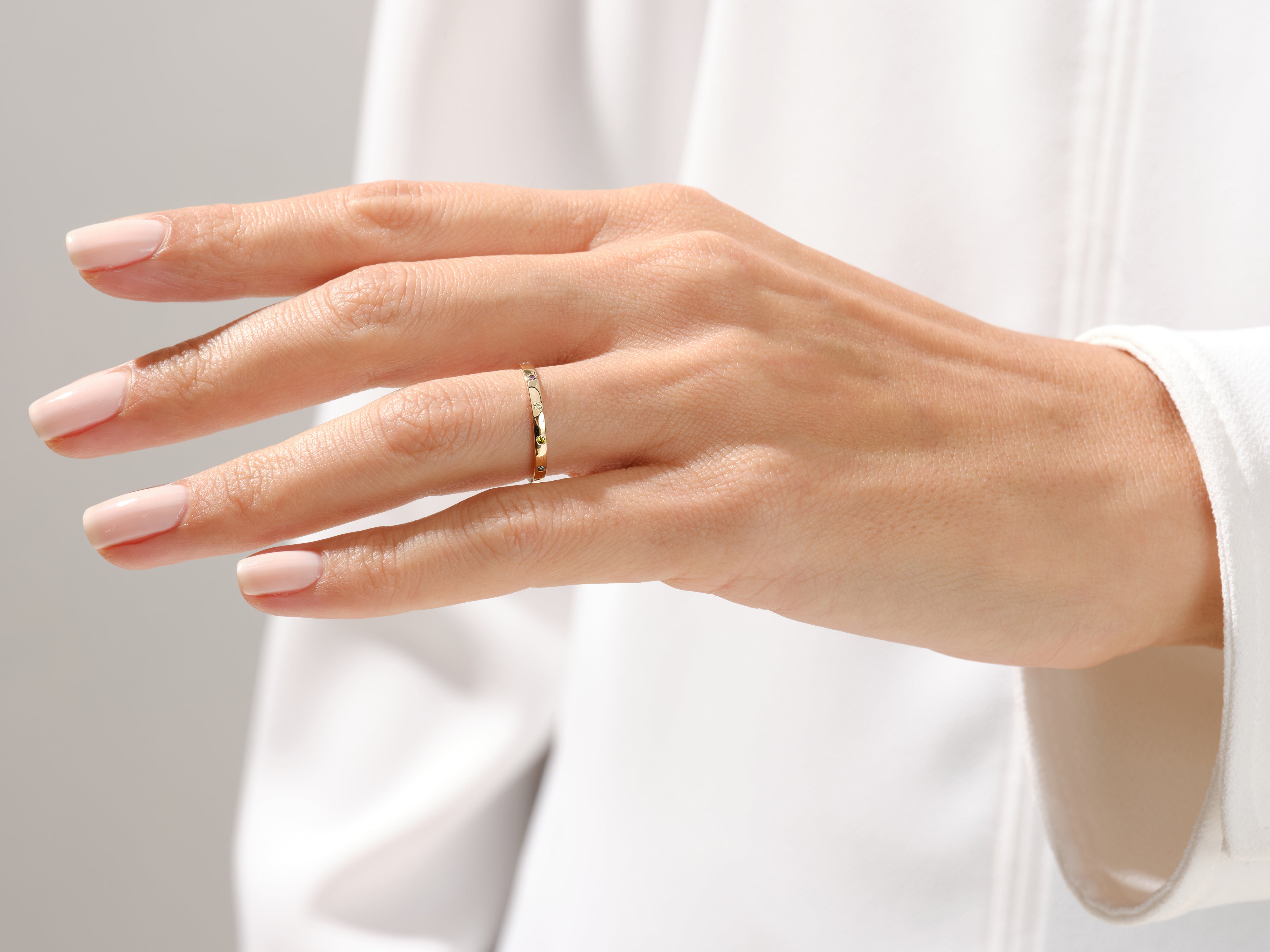Delicate gold ring with colorful gems on a woman's finger