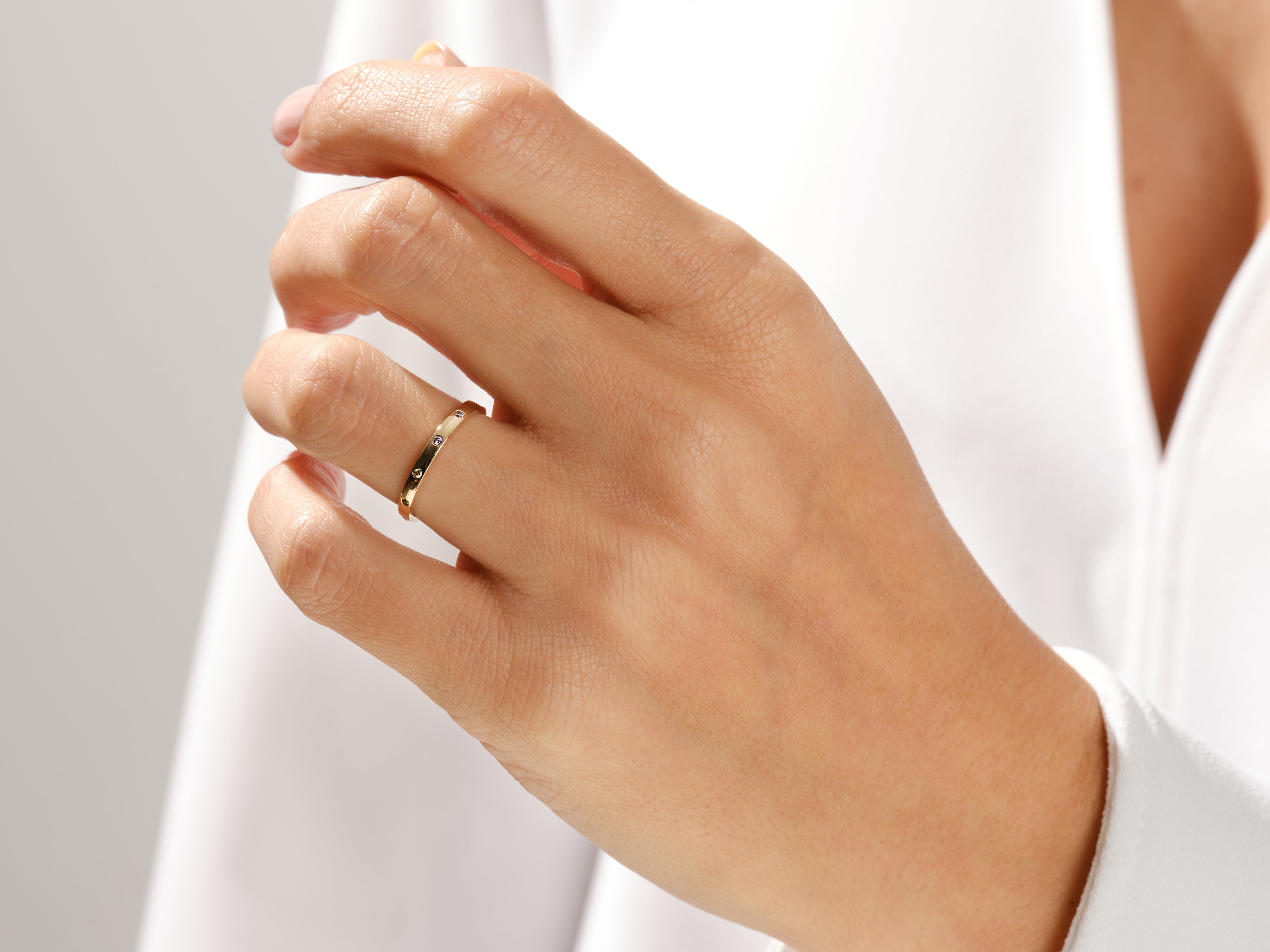 Gold band ring with scattered diamonds on a hand