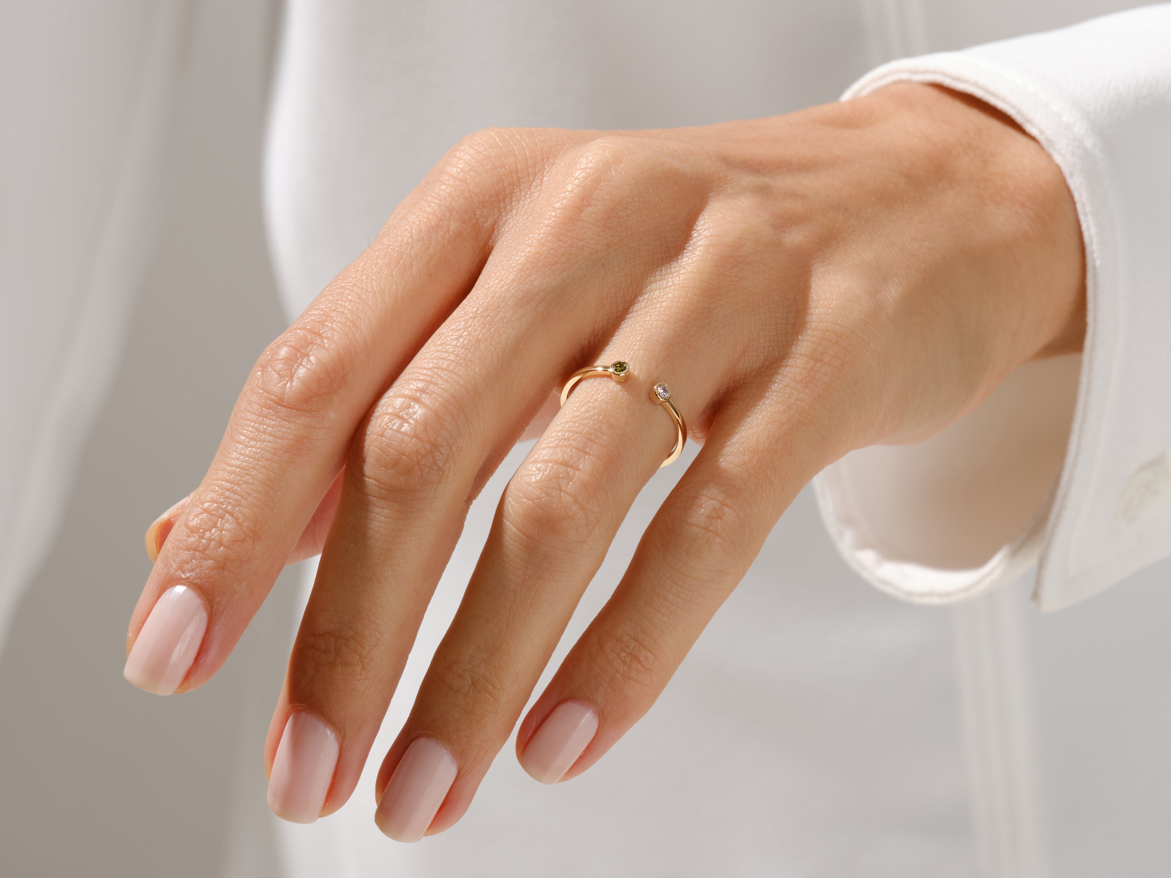 Gold open ring with diamonds and green gemstone on a woman's hand