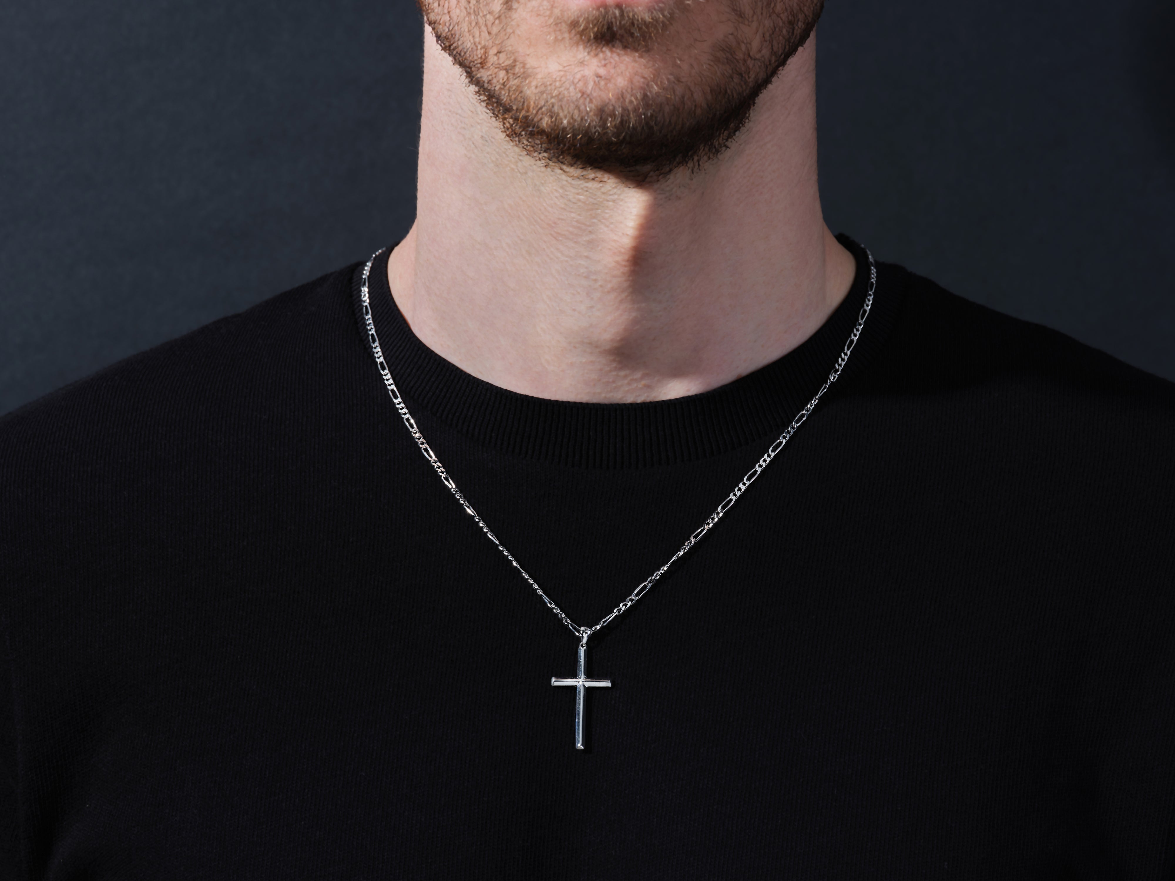 Men's silver cross necklace on black shirt