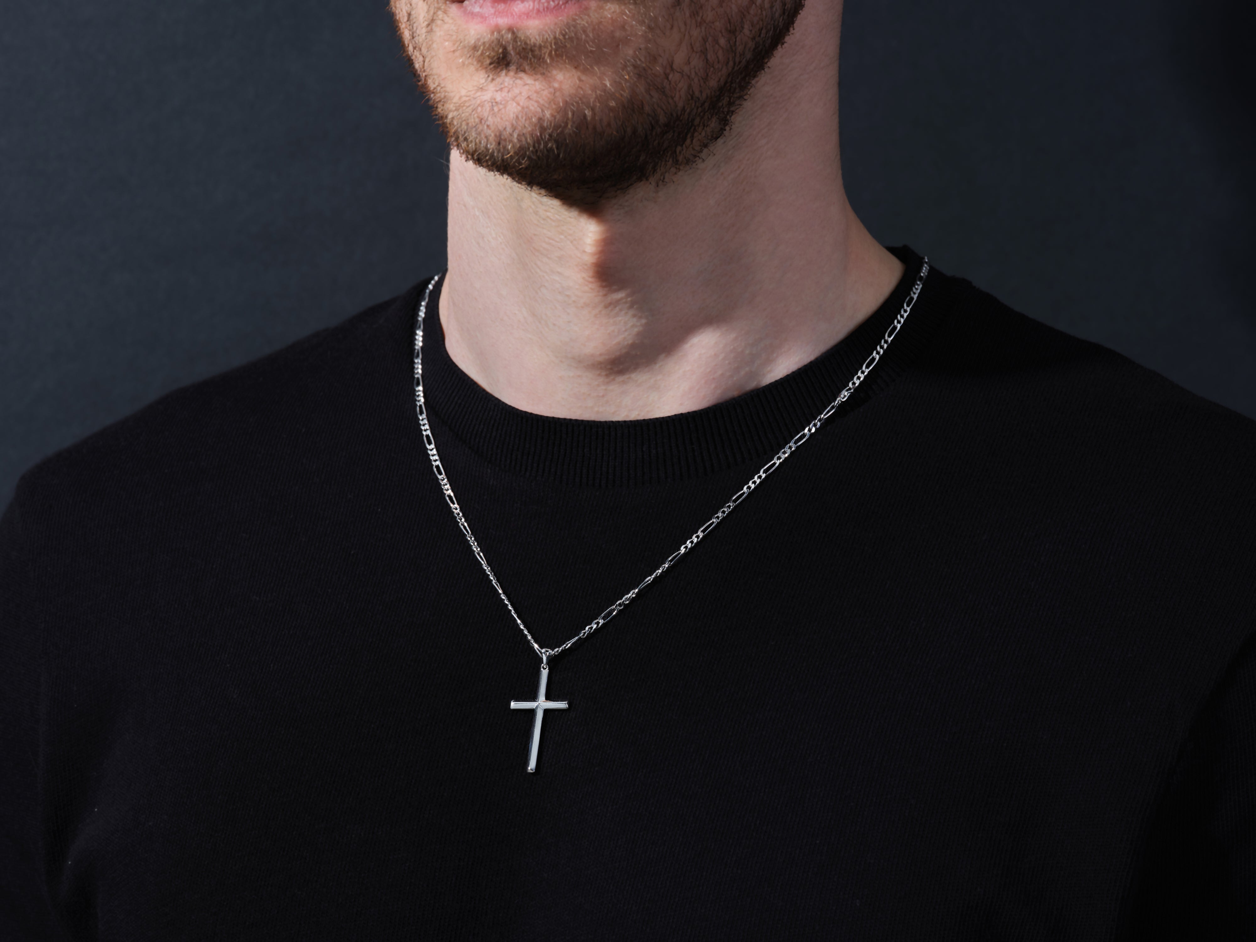 Men's silver cross necklace on black shirt