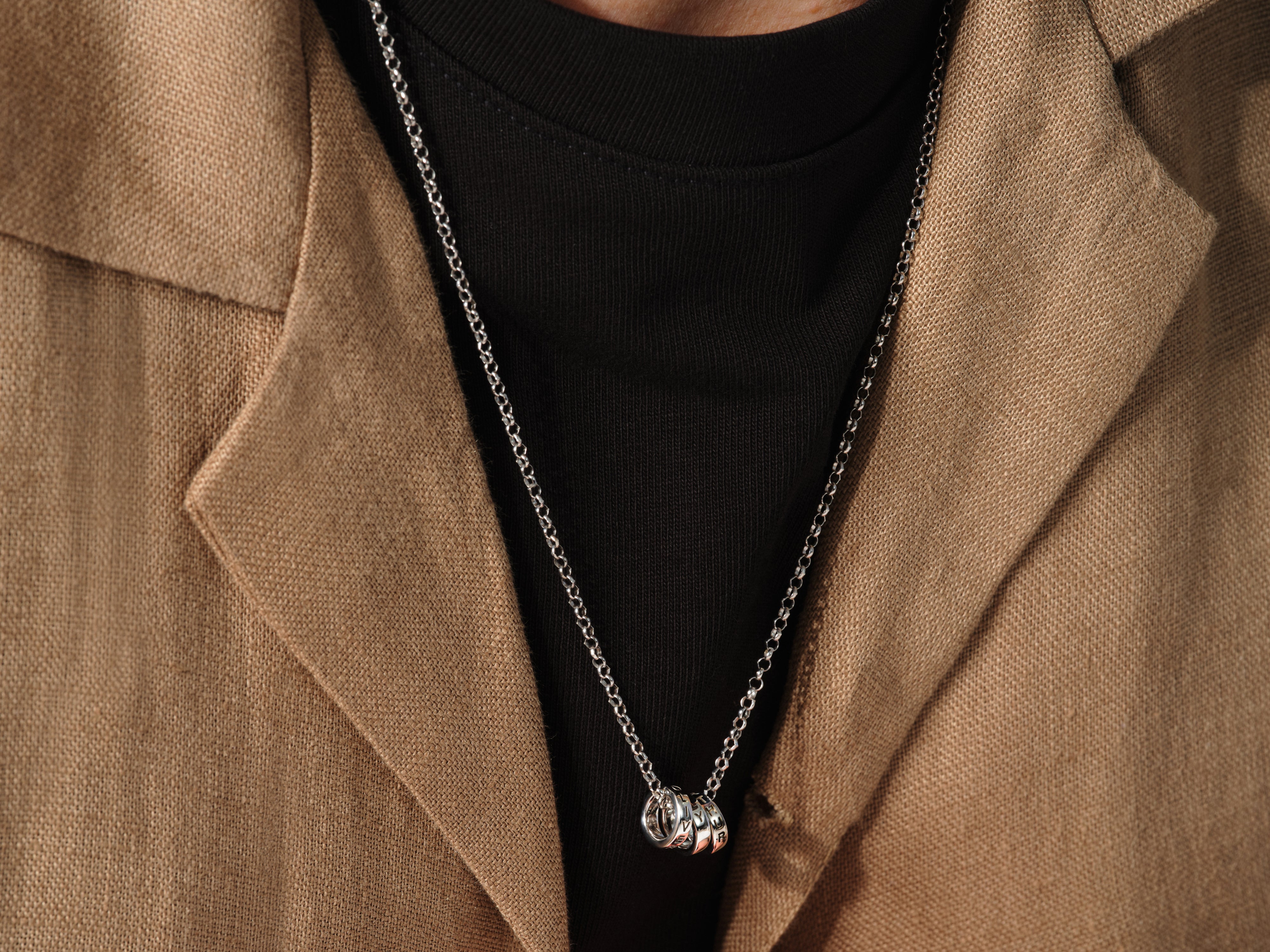Silver pendant necklace with engraved rings on a man