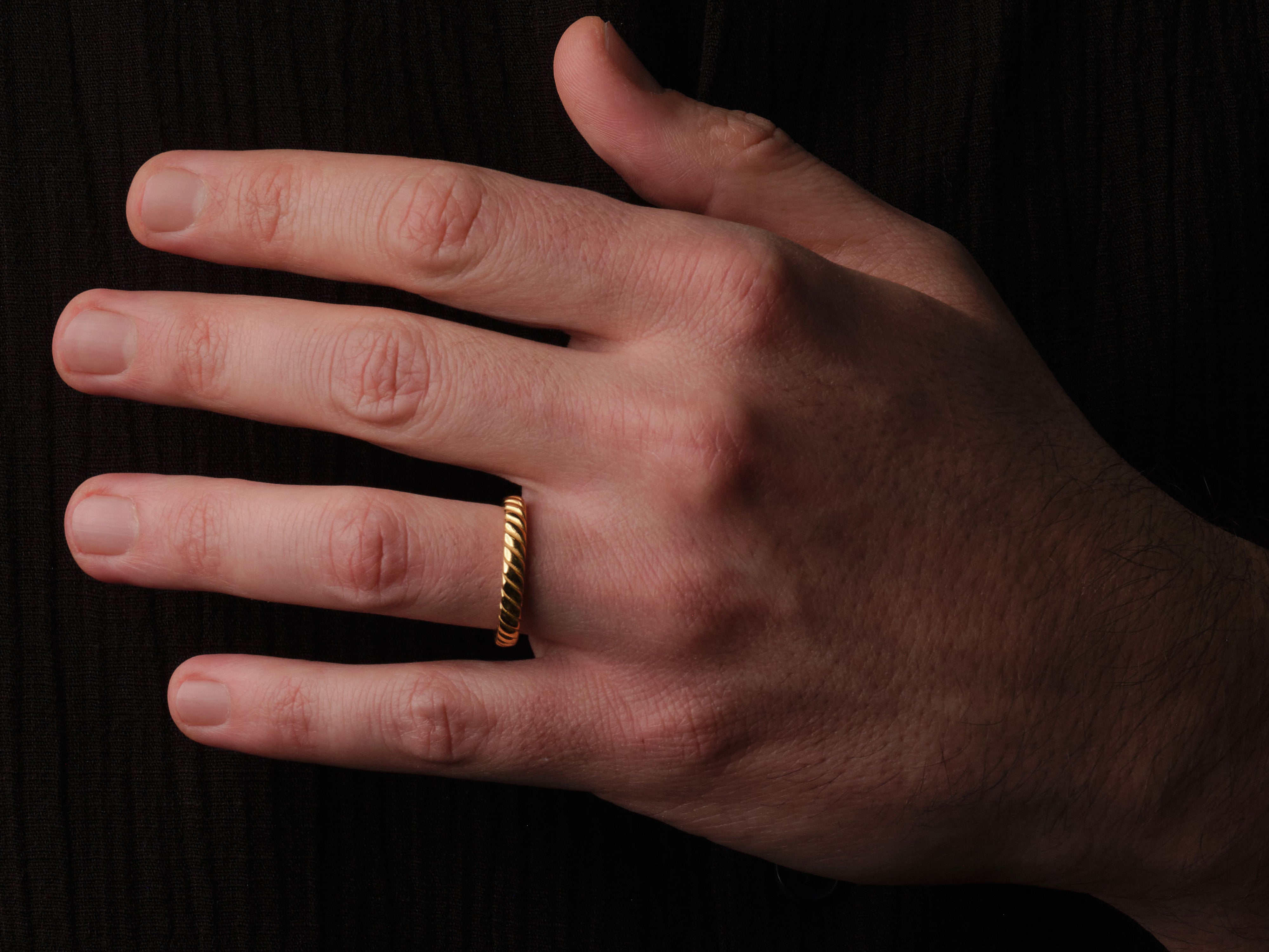 Gold twisted ring on a man's finger, fine jewelry